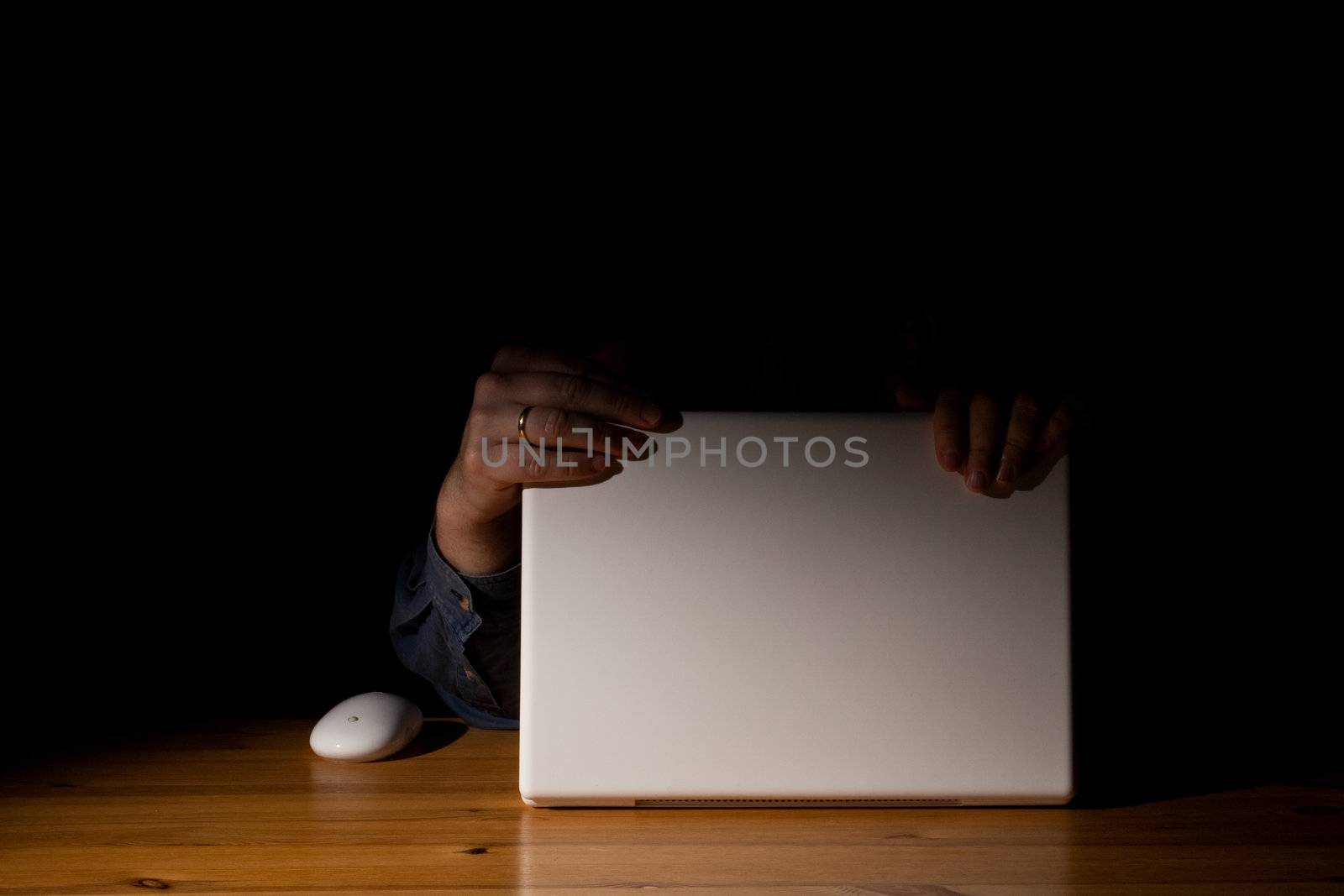 Two hands on a computer in the dark
