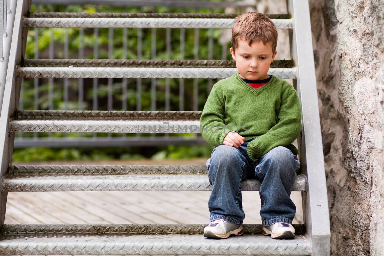 Sad little boy sitting alone on stairs