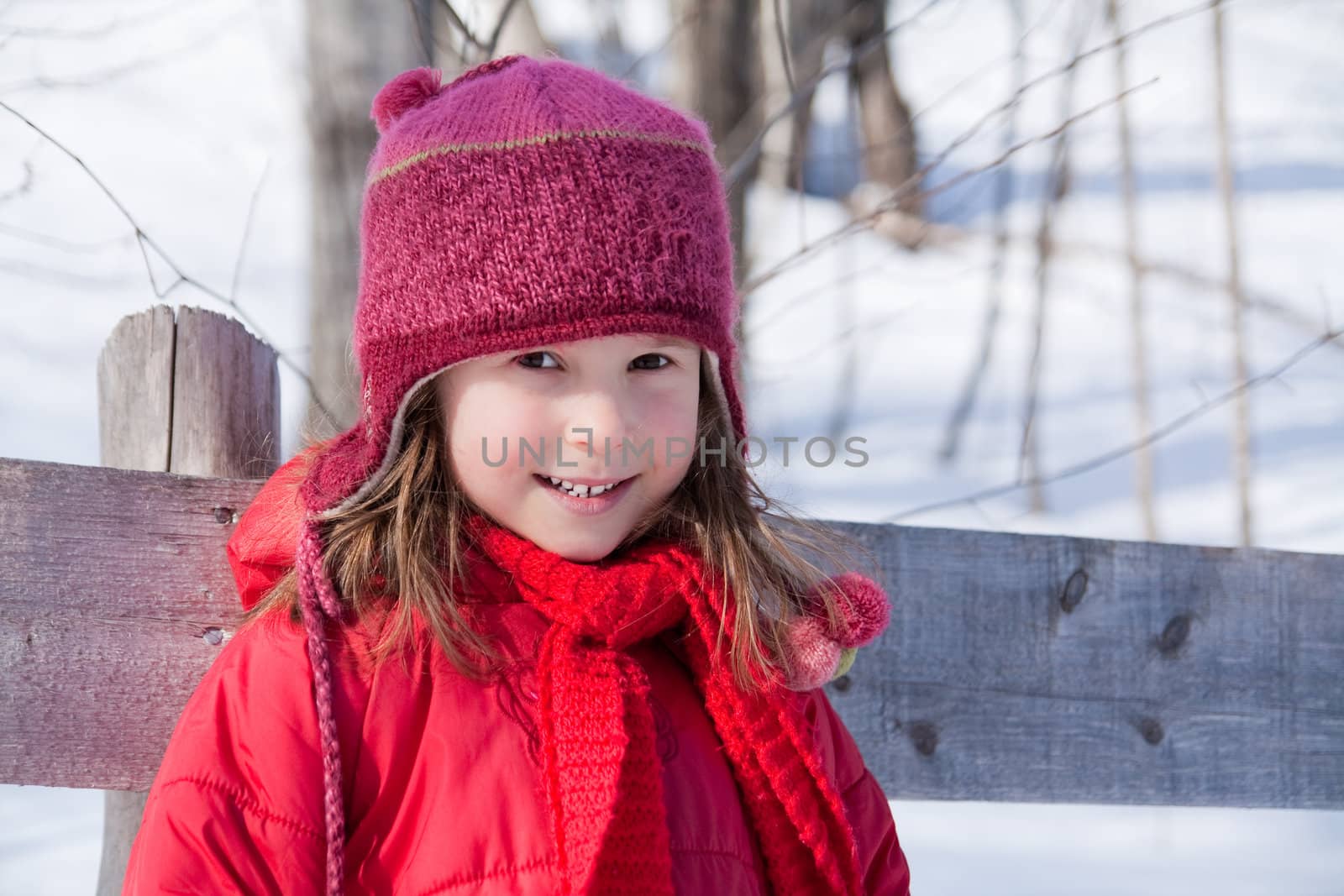 Cute little girl standing by a fence in winter