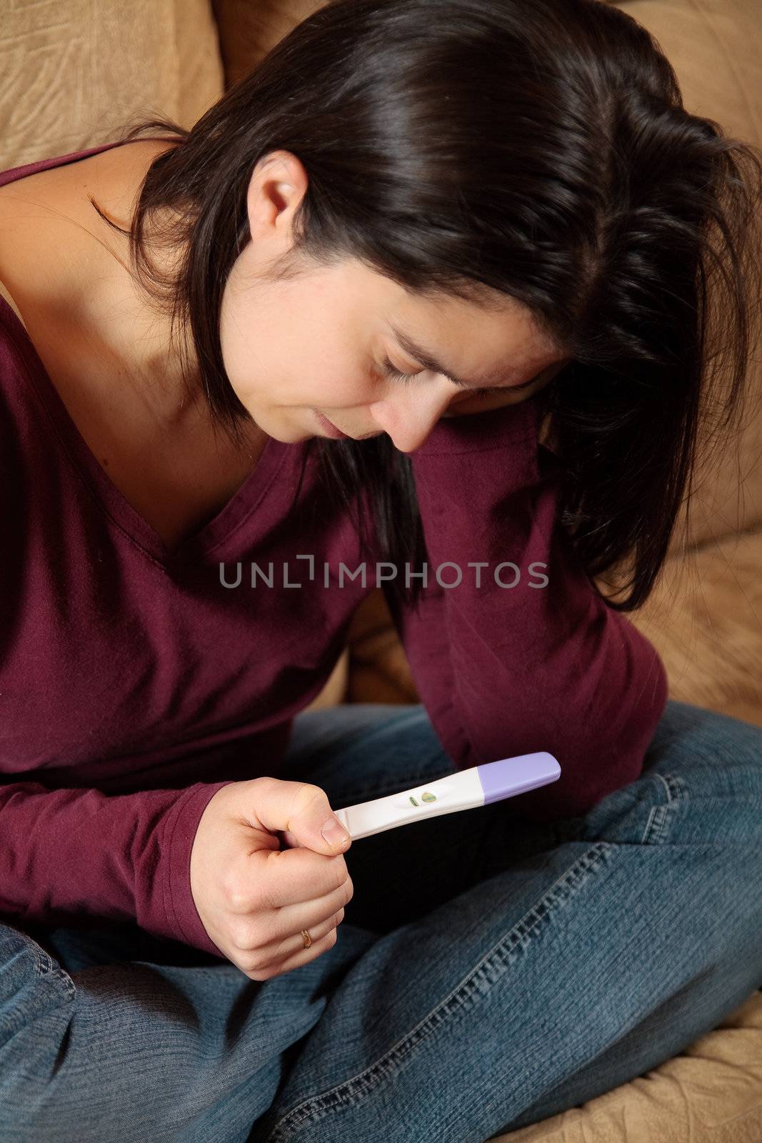 Sad woman looking at a positive pregnancy test