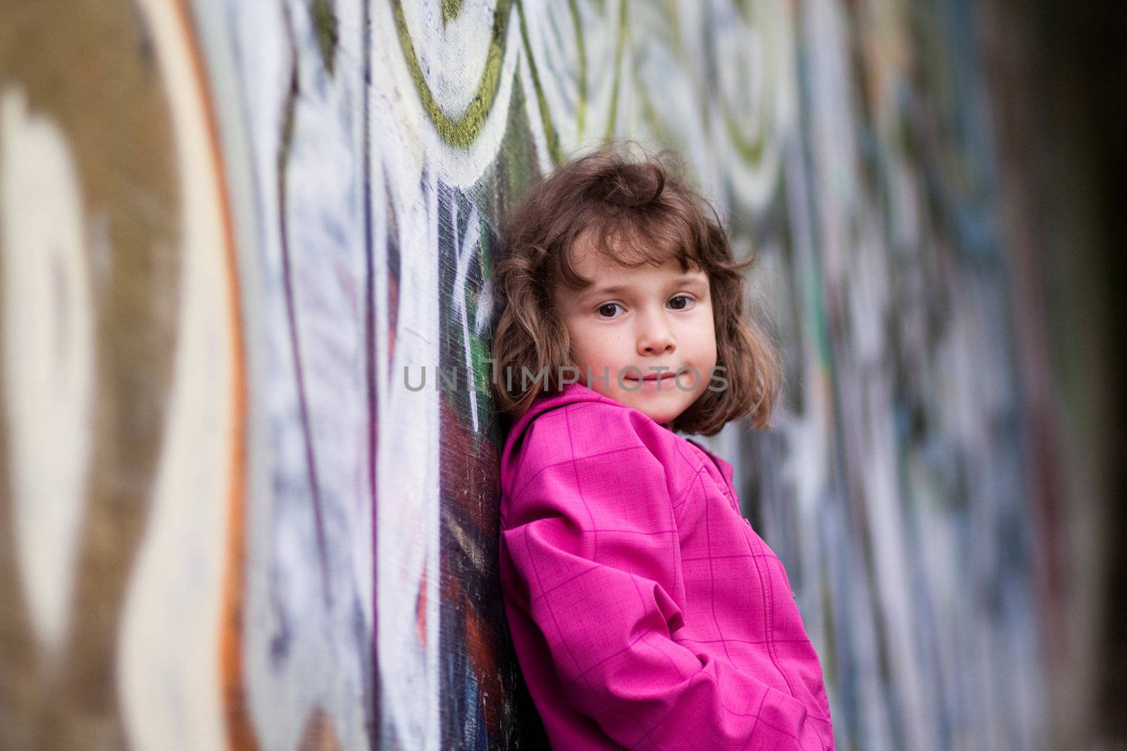 Little girl standing in front of a wall with graffiti
