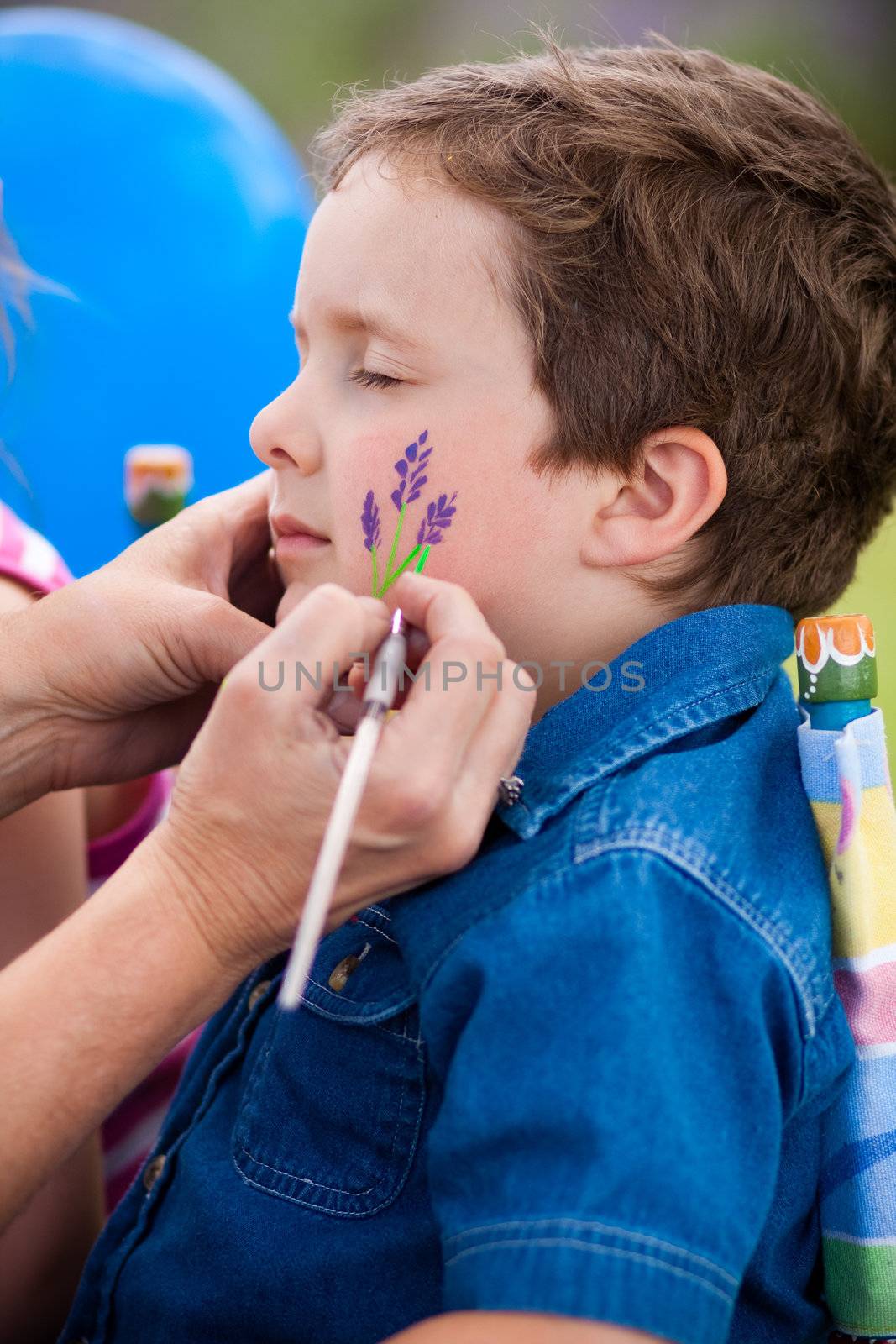 Cute little boy getting make-up on his face