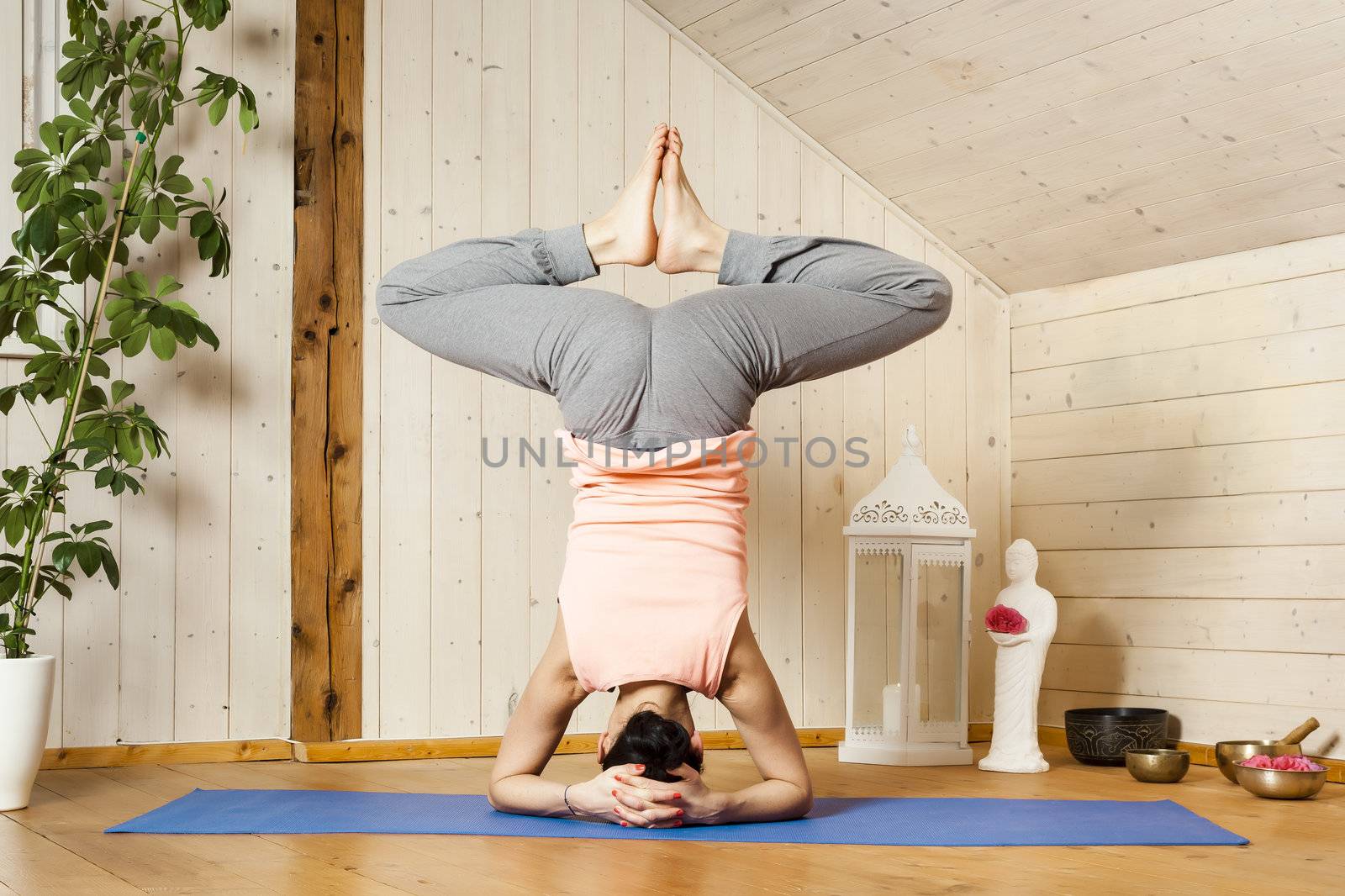 An image of a pretty woman doing yoga at home - Baddha Konasana Shirshasana
