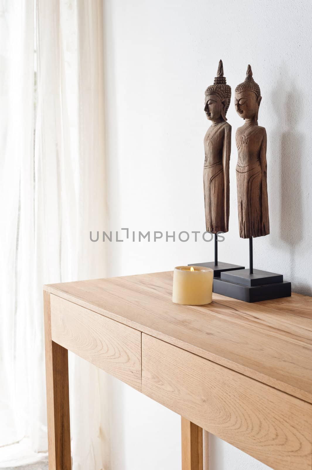 Two Buddha figurine in front of a white wall