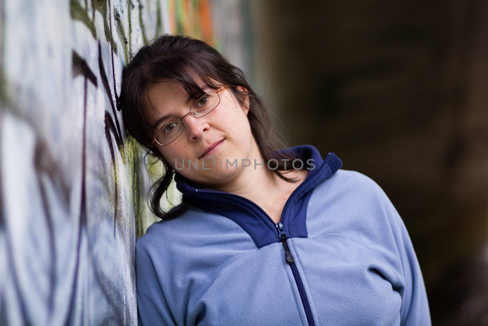 Young woman standing in front of a wall with graffiti