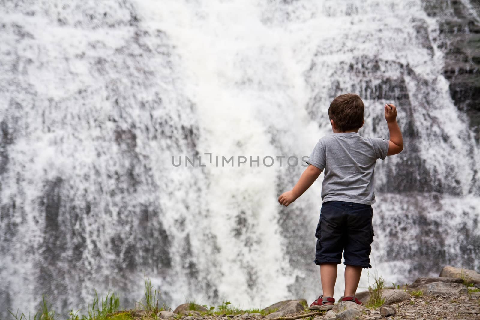 Little boy throwing rocks in a waterfall