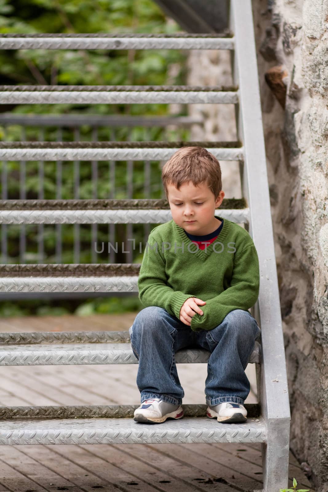 Sad little boy sitting alone on stairs