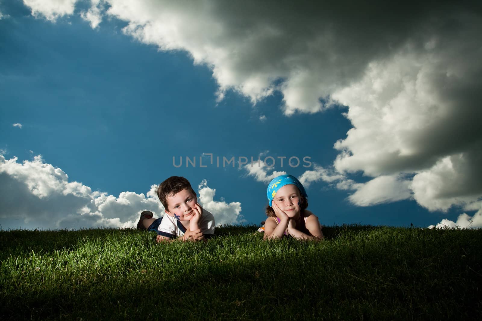 Girl and boy laying on the grass by Talanis
