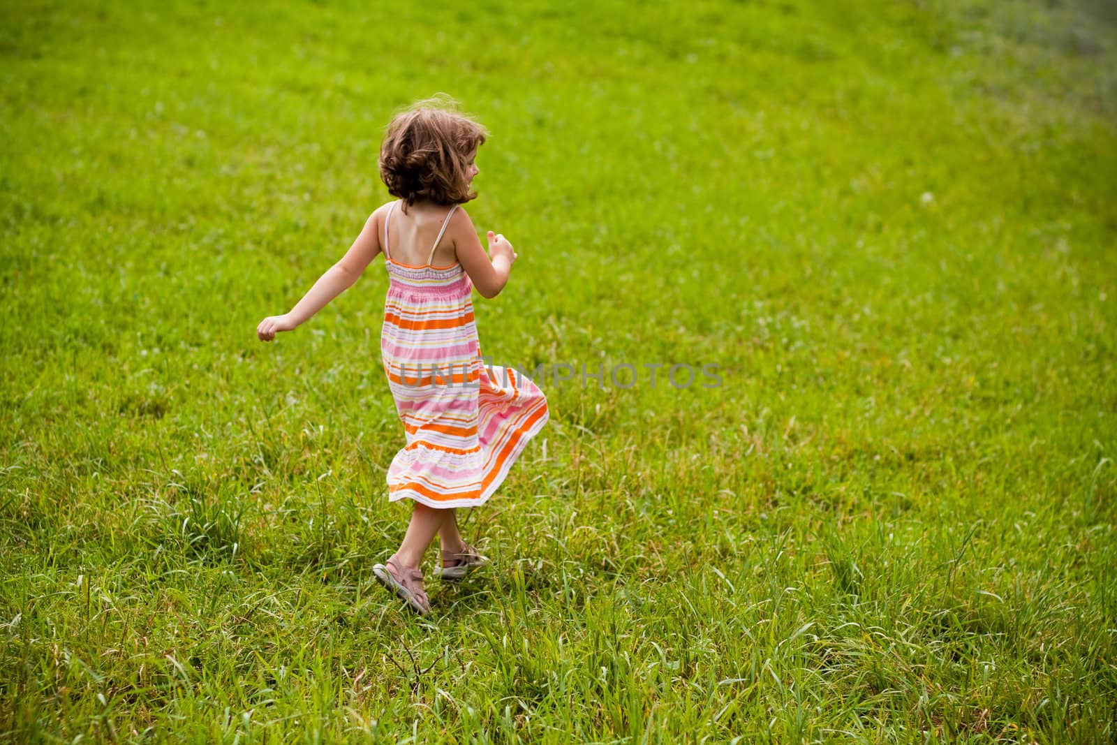 Cute little girl running in a grass field