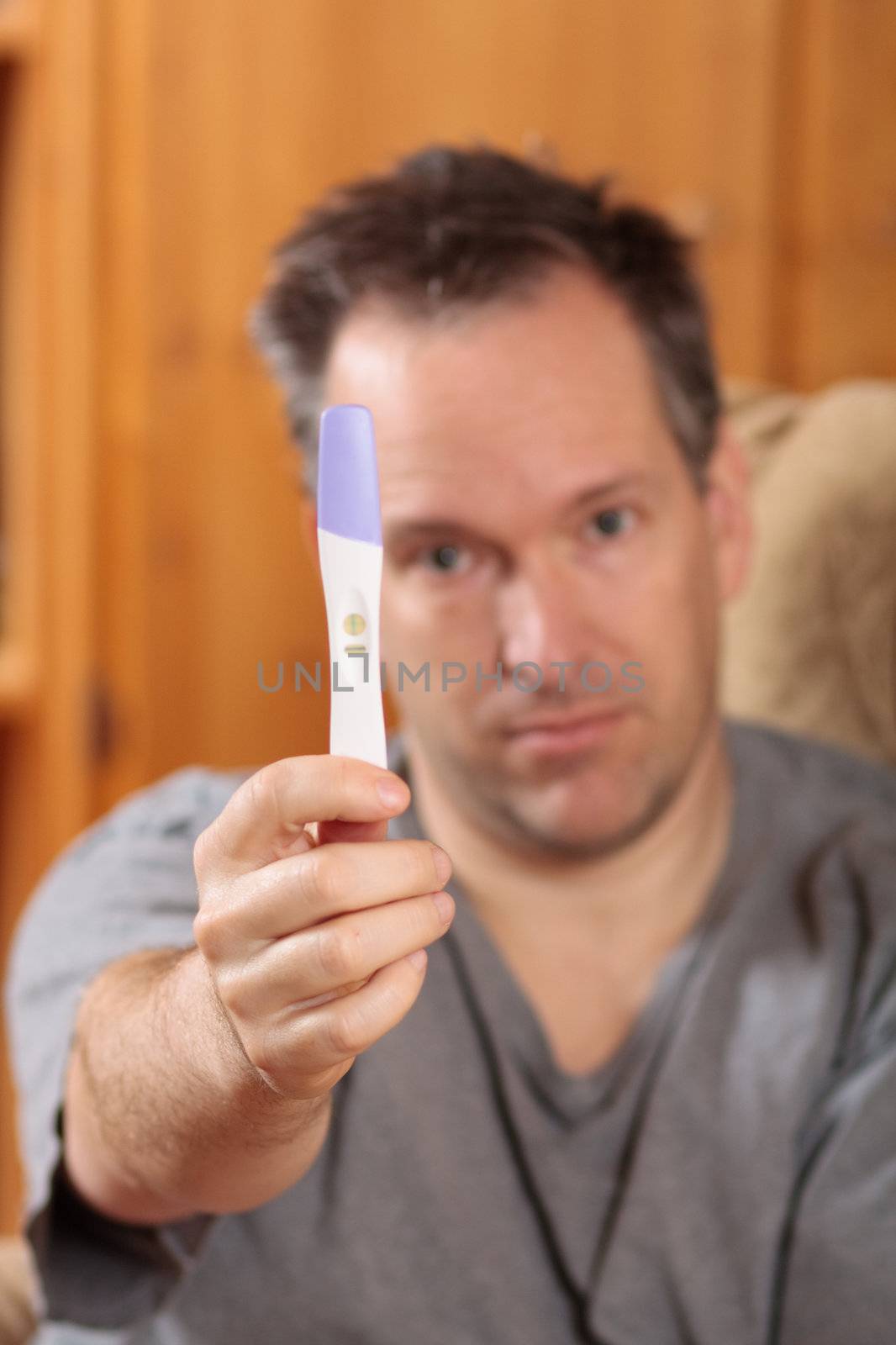 Sad man holding a positive pregnancy test
