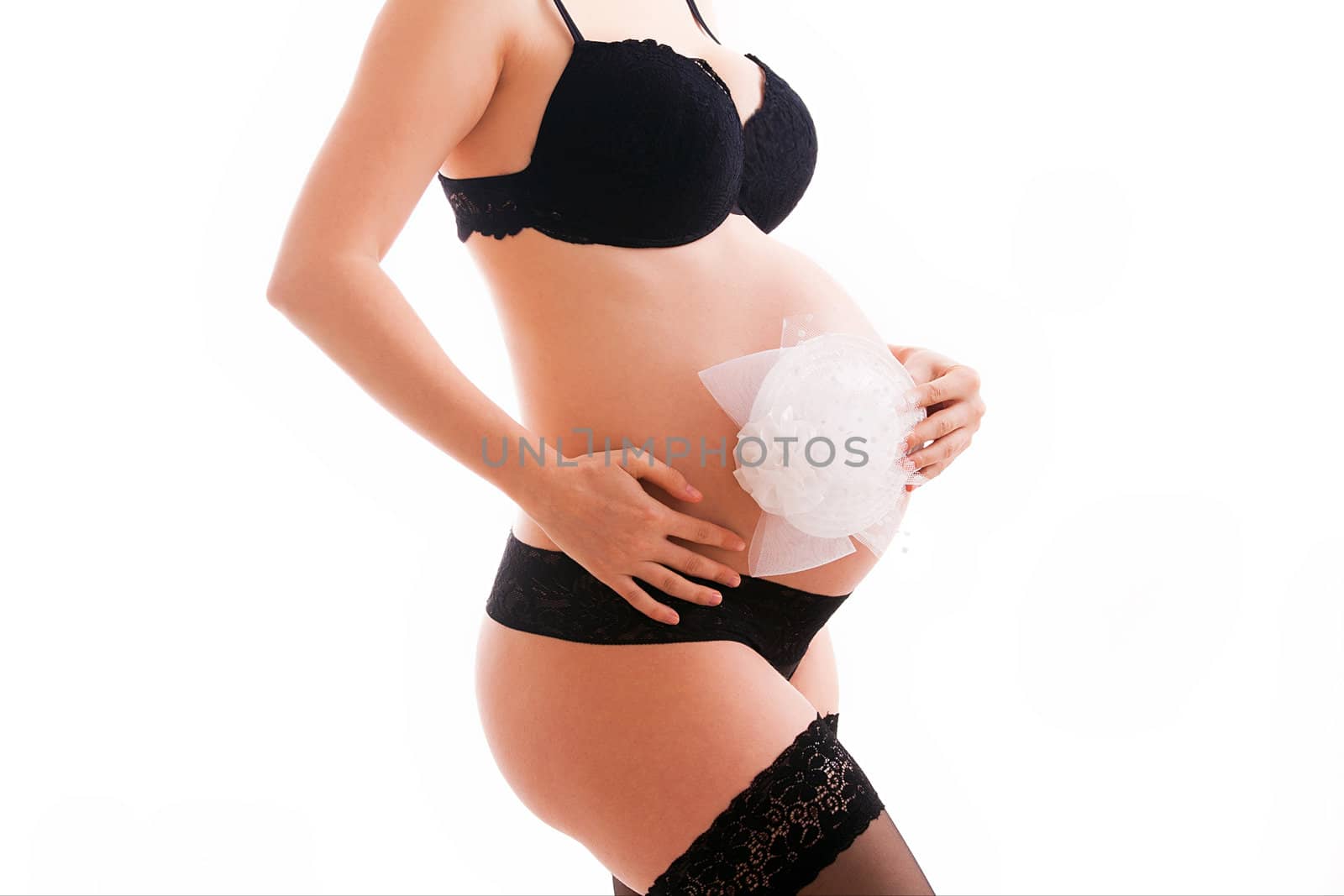 Pregnant woman wearing lingerie holding her belly 