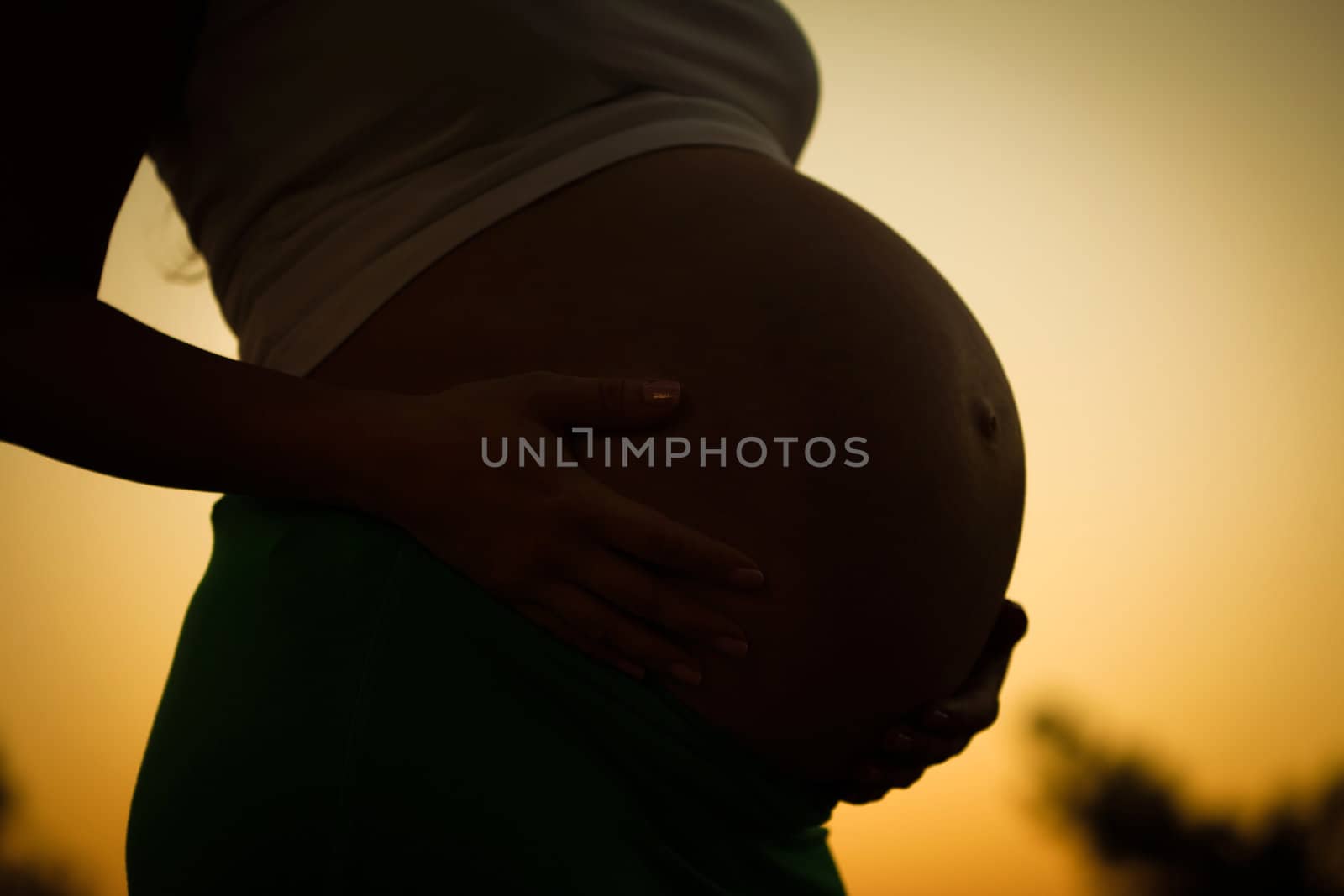 Pregnant woman holding belly with arms 9 month 