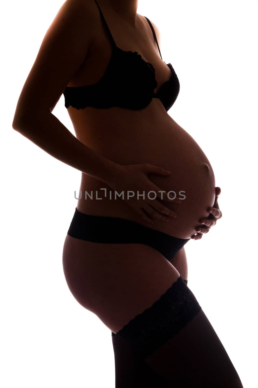 Pregnant woman wearing lingerie holding her belly