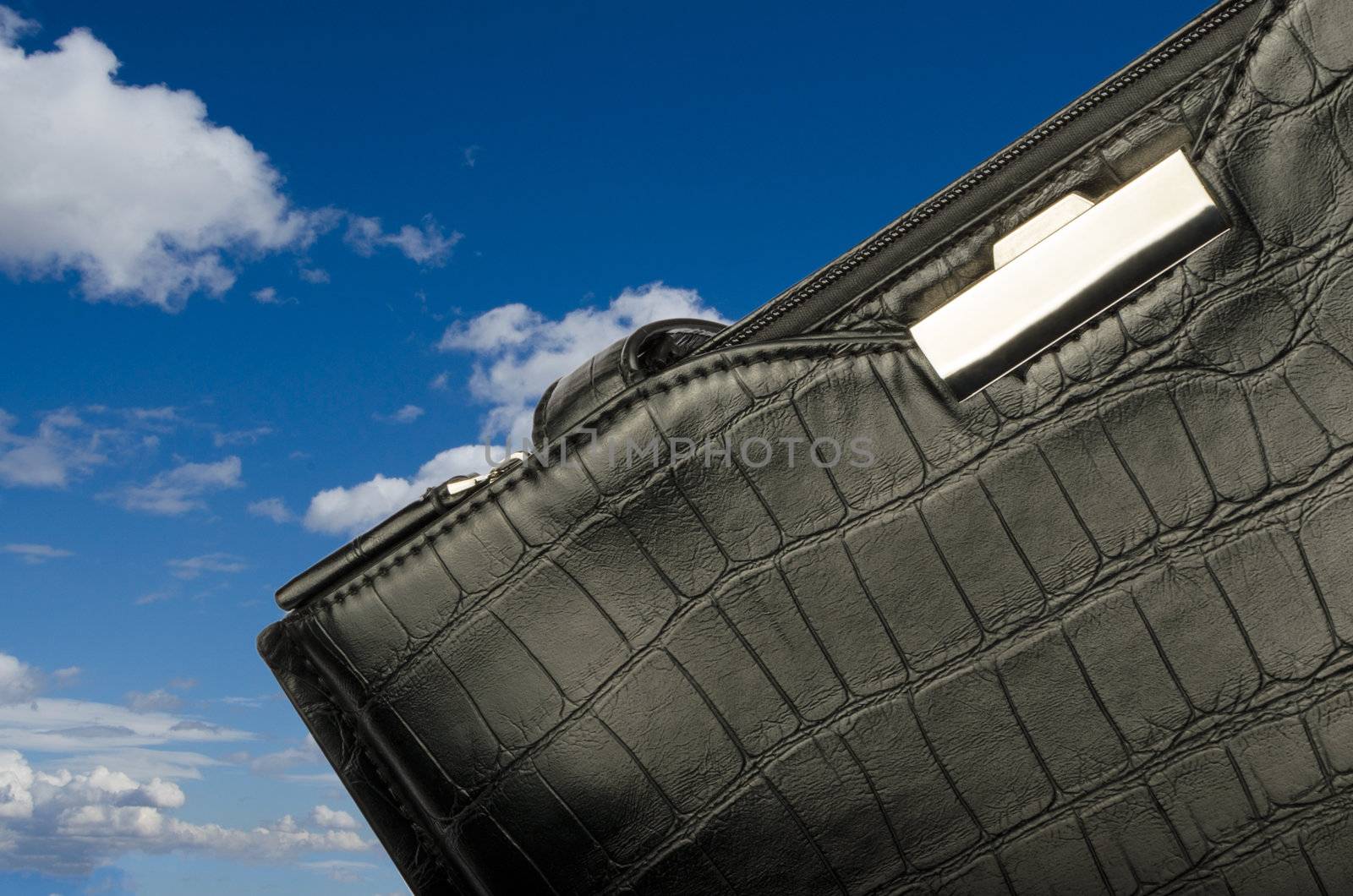 A black business bag on background of sky and clouds