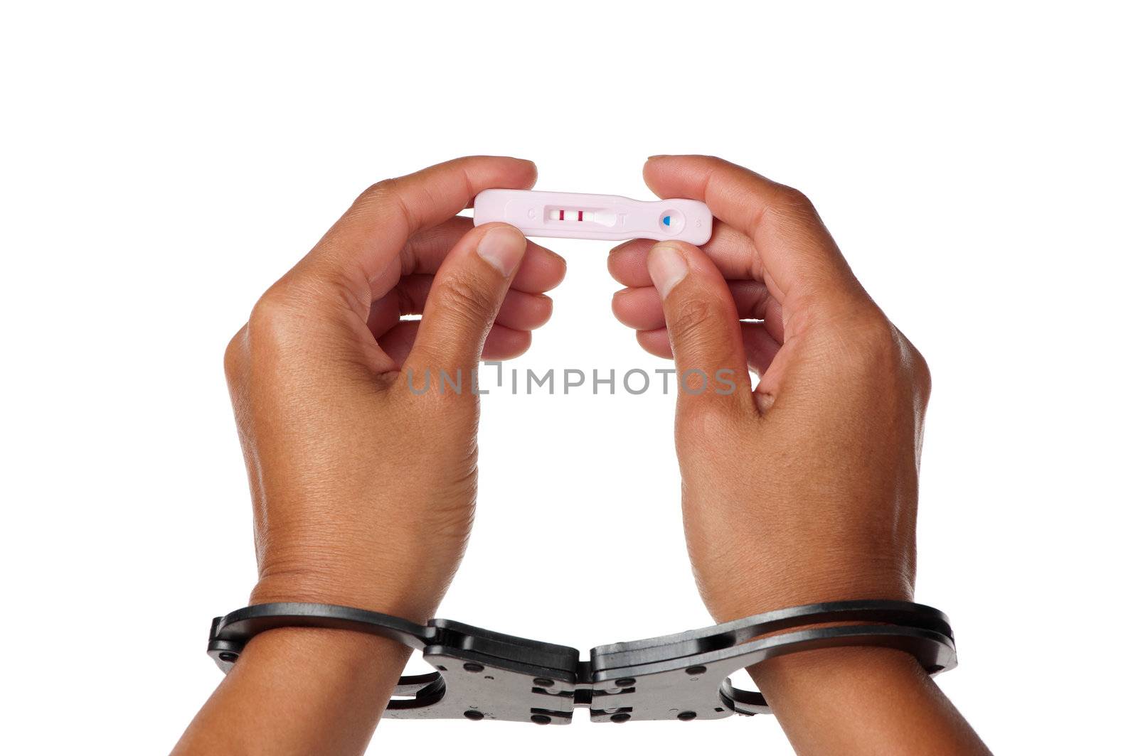 Female handcuffed hands hold a positive pregnancy test up high.