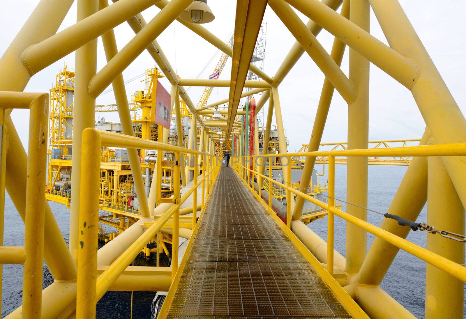 the worker is walking cross the pathway bridge of offshore oil rig