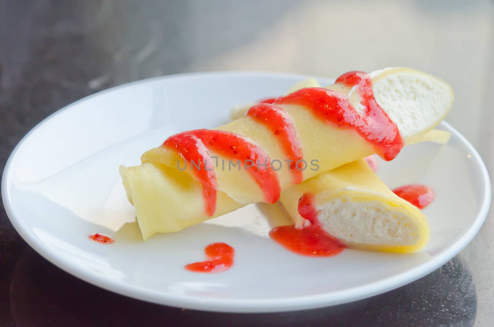 crepe rolls filled  with white cream , topping with strawberry  sauce