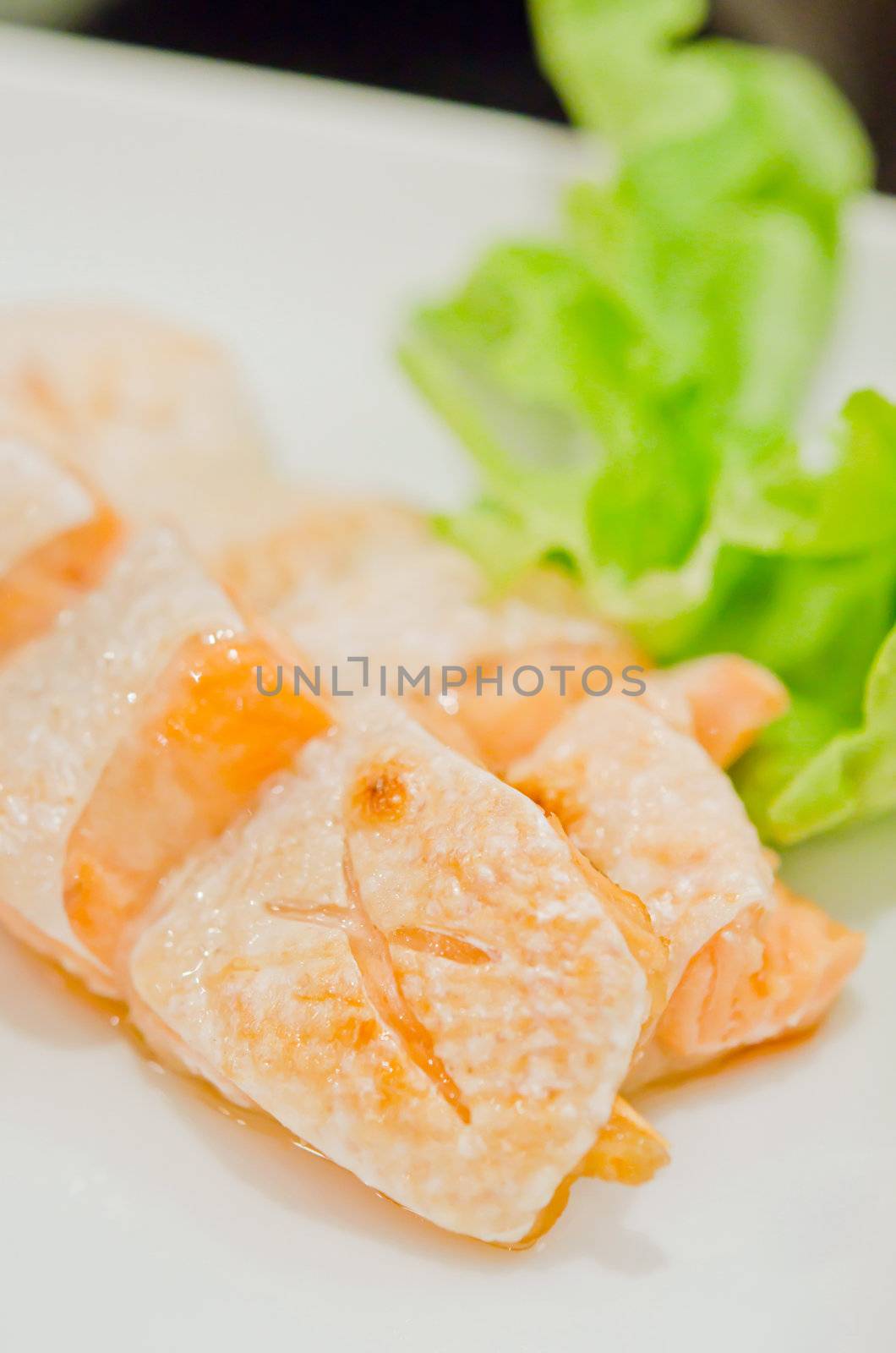 Grilled salmon belly served with fresh lettuce on dish