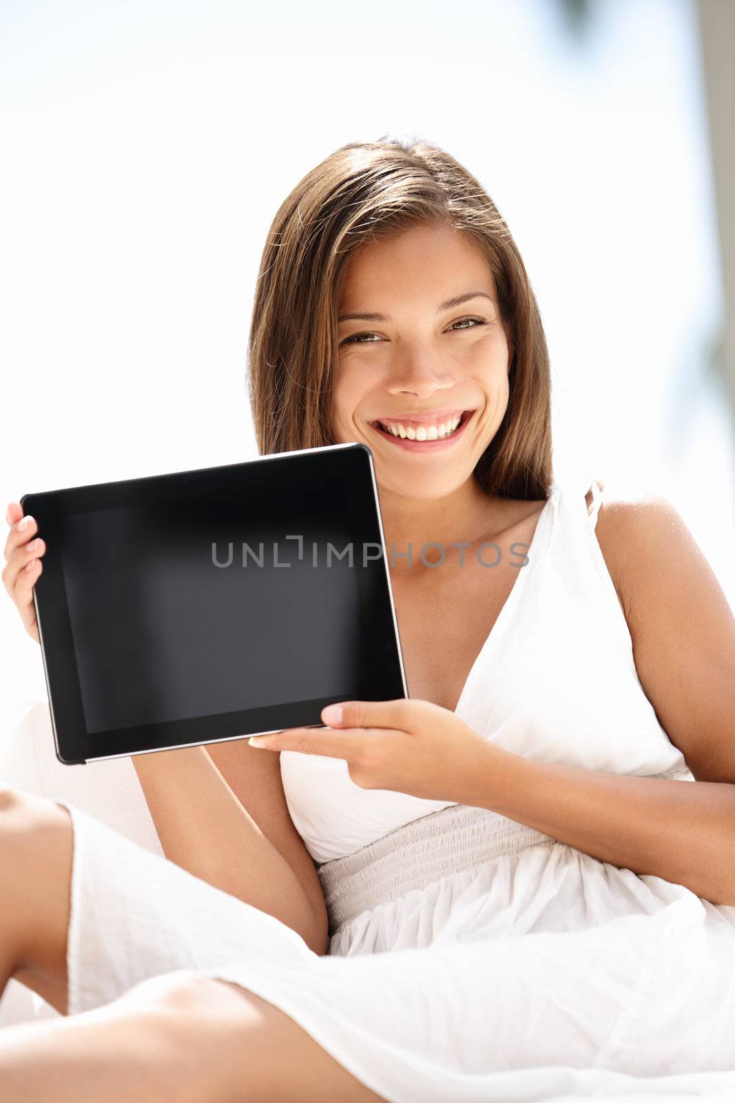 Tablet pc computer woman smiling happy. Person holding showing blank tablet computer touch screen sitting outdoors in luxury setting. Beautiful joyful mixed race Asian Cauasian female model outside.