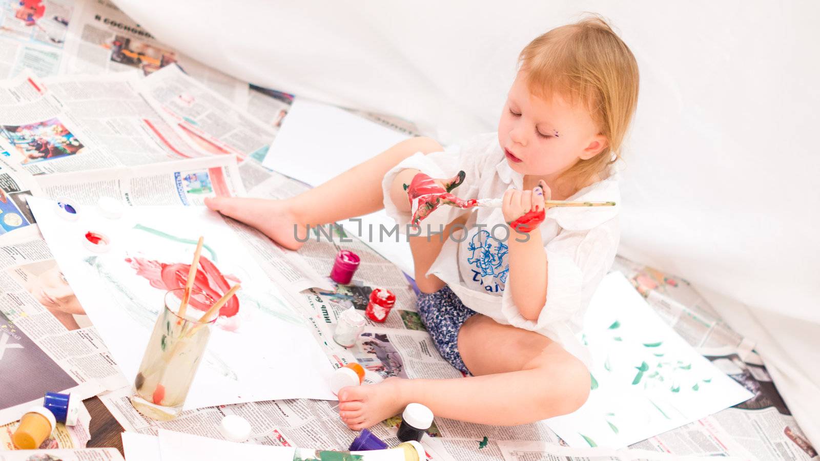 cheerful child draws pictures on newspapers by natochka