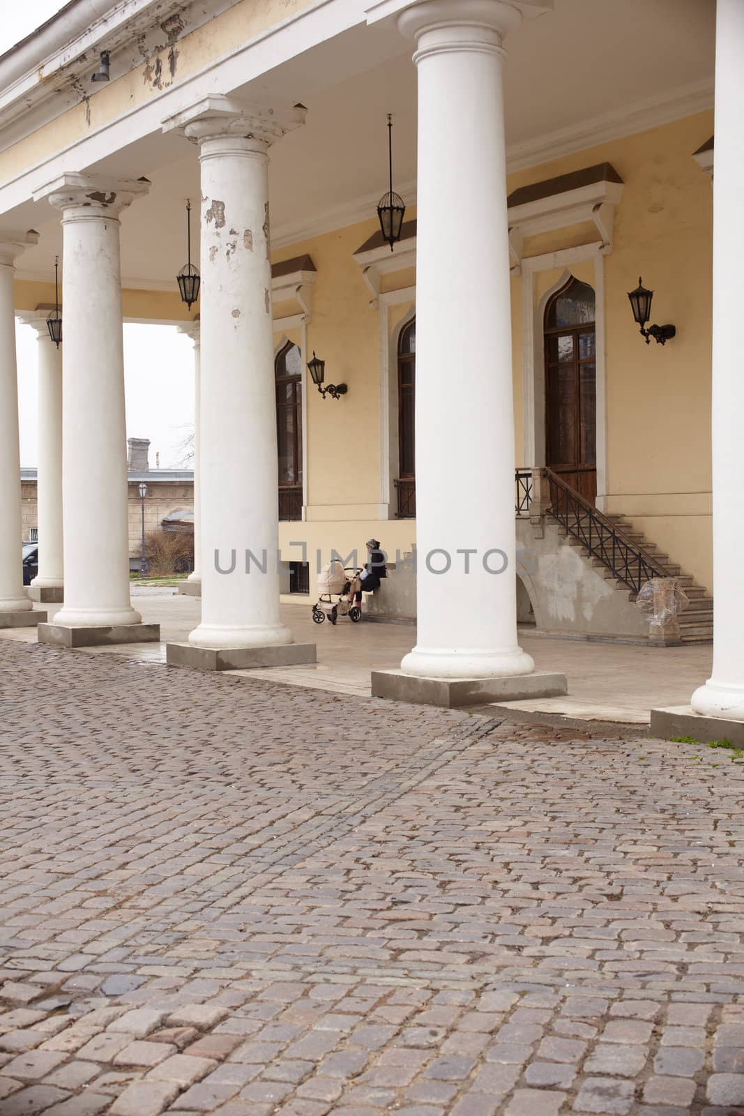Woman with baby carriage next to a colonnade in Odessa