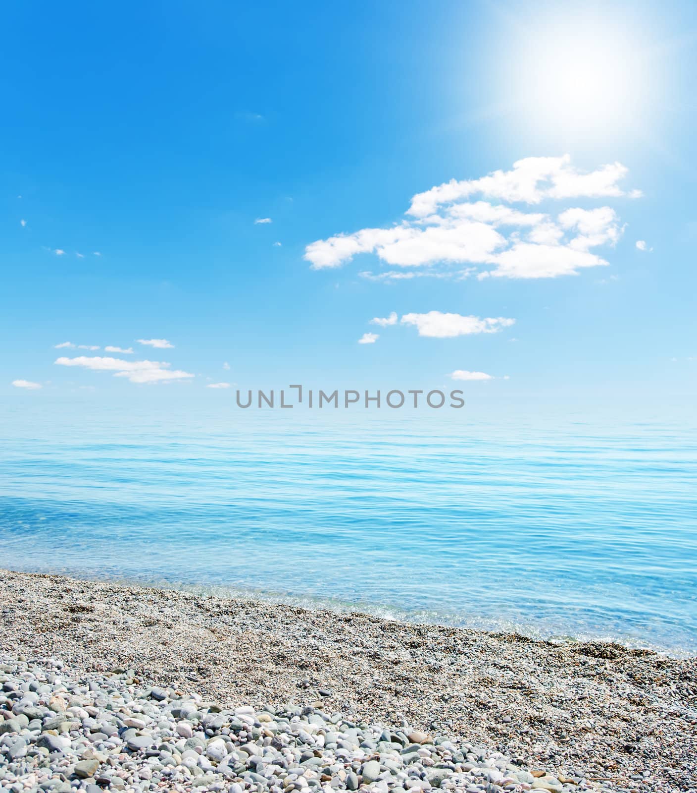 sun over beach with stones by mycola