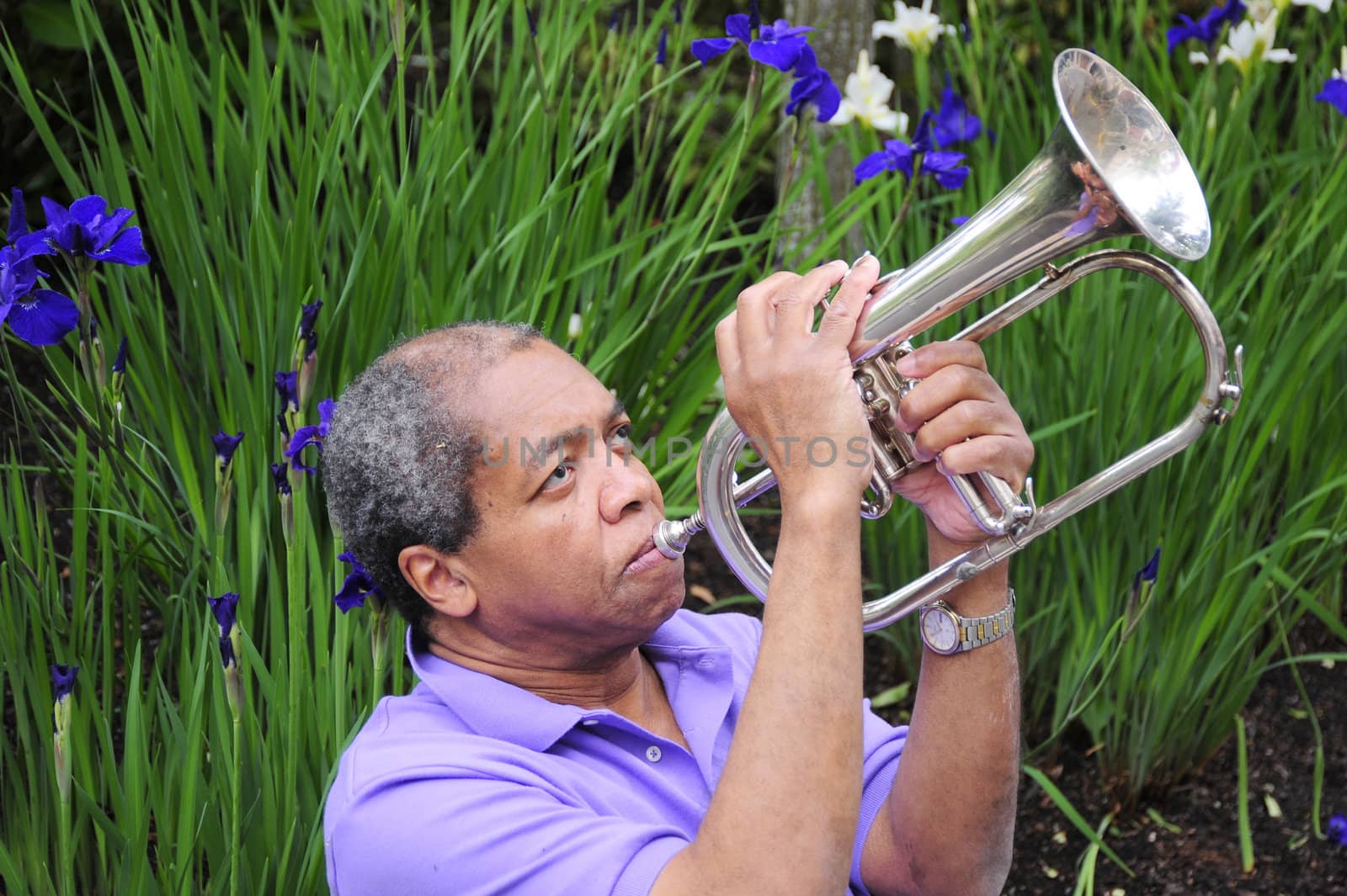 African American male with his flugelhorn outdoors.