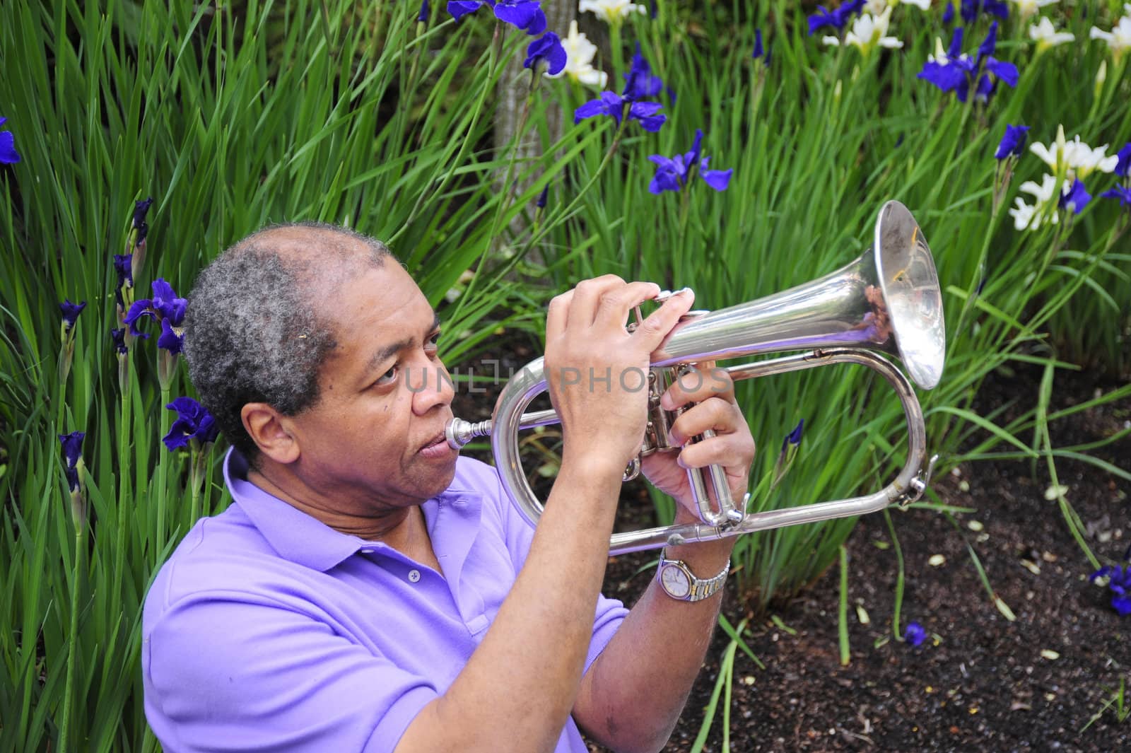 African American male with his flugelhorn outdoors.
