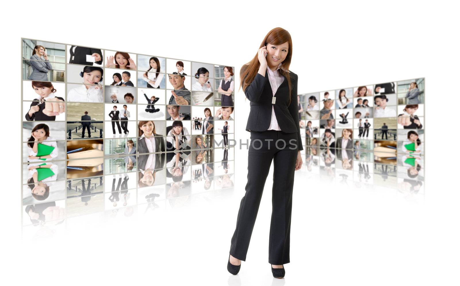 Business woman talk on cellphone in front of video wall. Business conferencing and global communications concept.