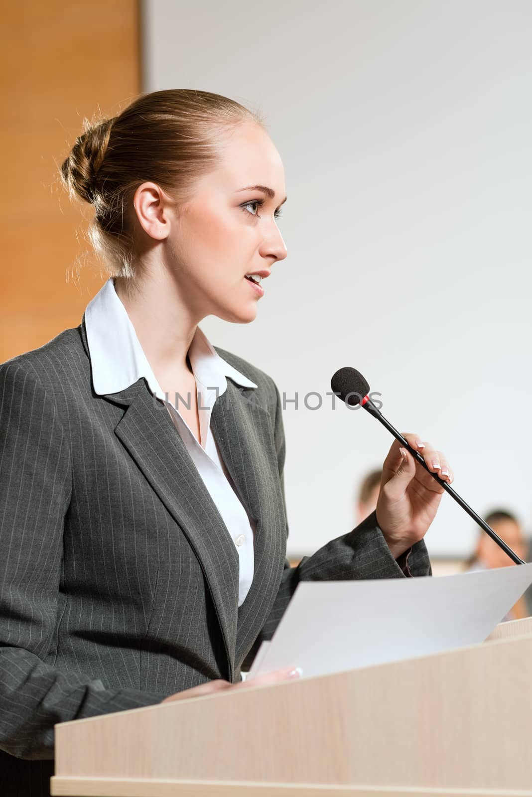 Portrait of a business woman holding a microphone and looks ahead