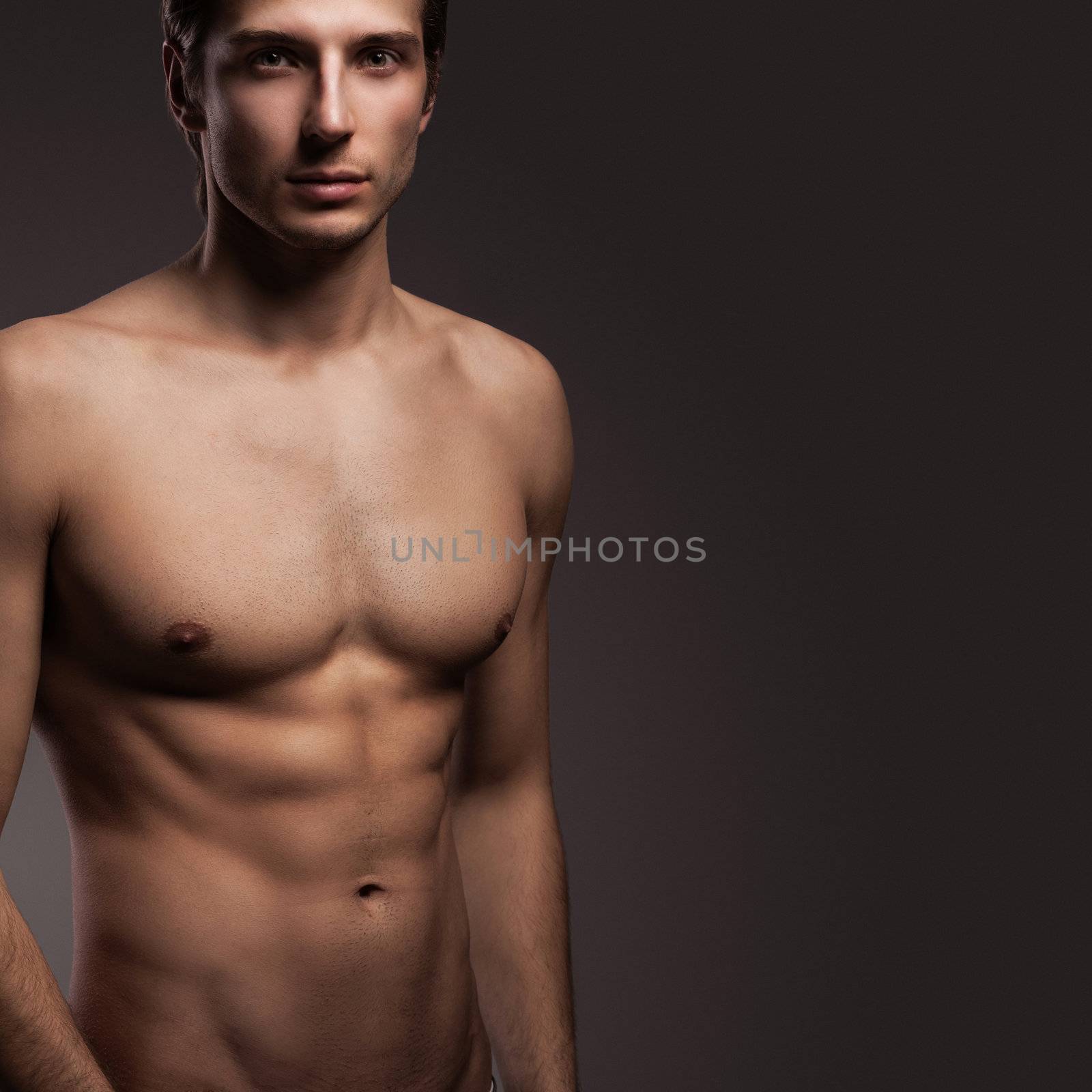 Handsome young man with naked torso on a grey background