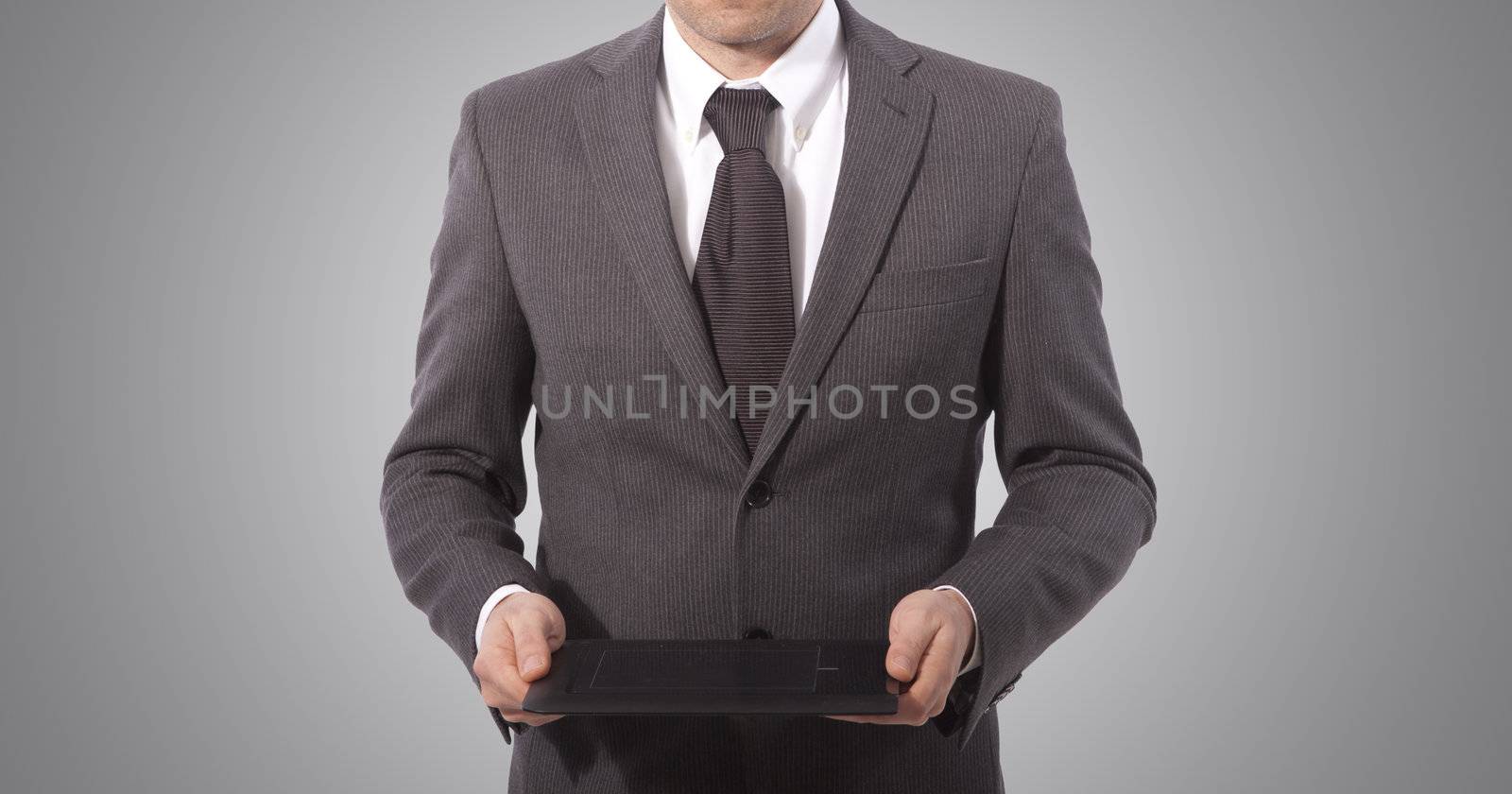 business man with touch tablet in hands, grey background. 