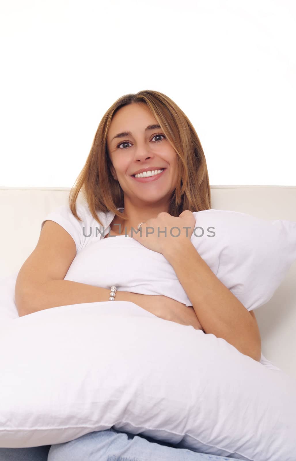 smiling young woman embracing cushion pillow by matteobragaglio