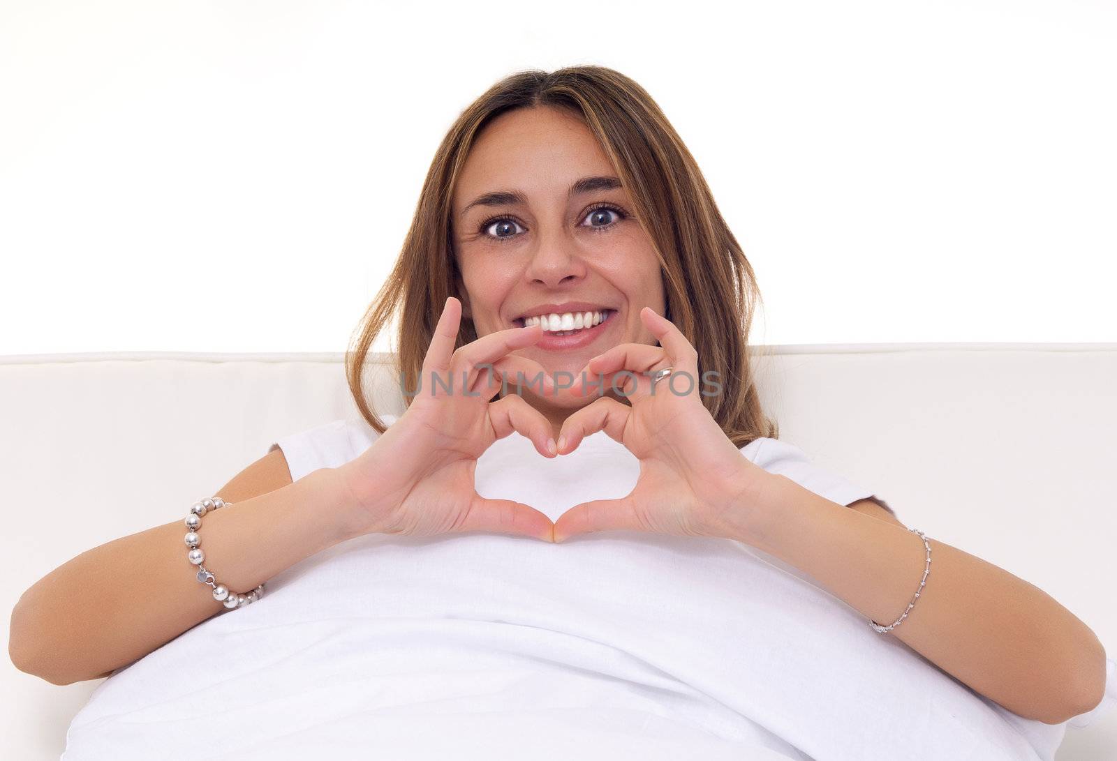 young woman make heart shape with finger while smiling by matteobragaglio