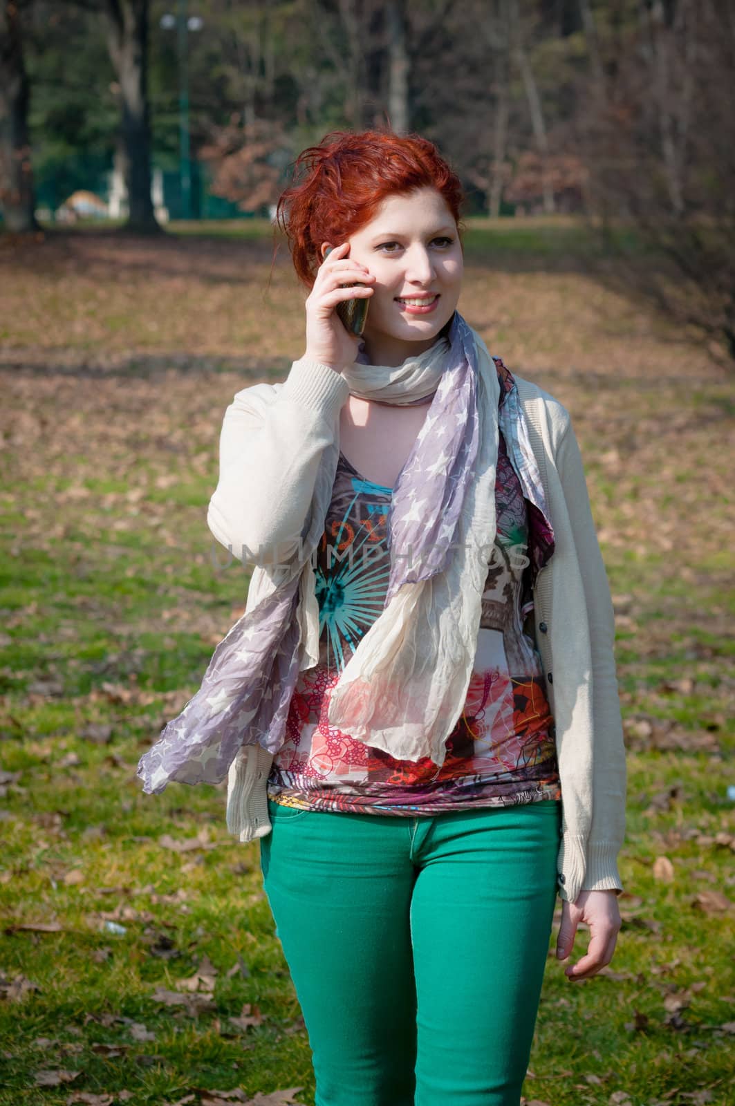 red long hair girl at the park on the phone in spring 