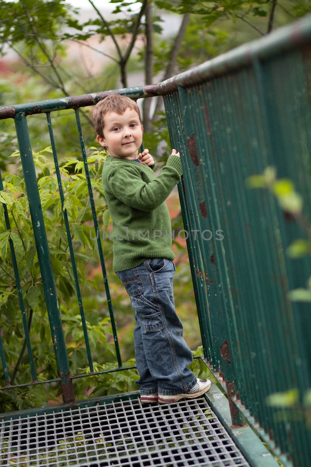 Young boy smiling by a metal fence
