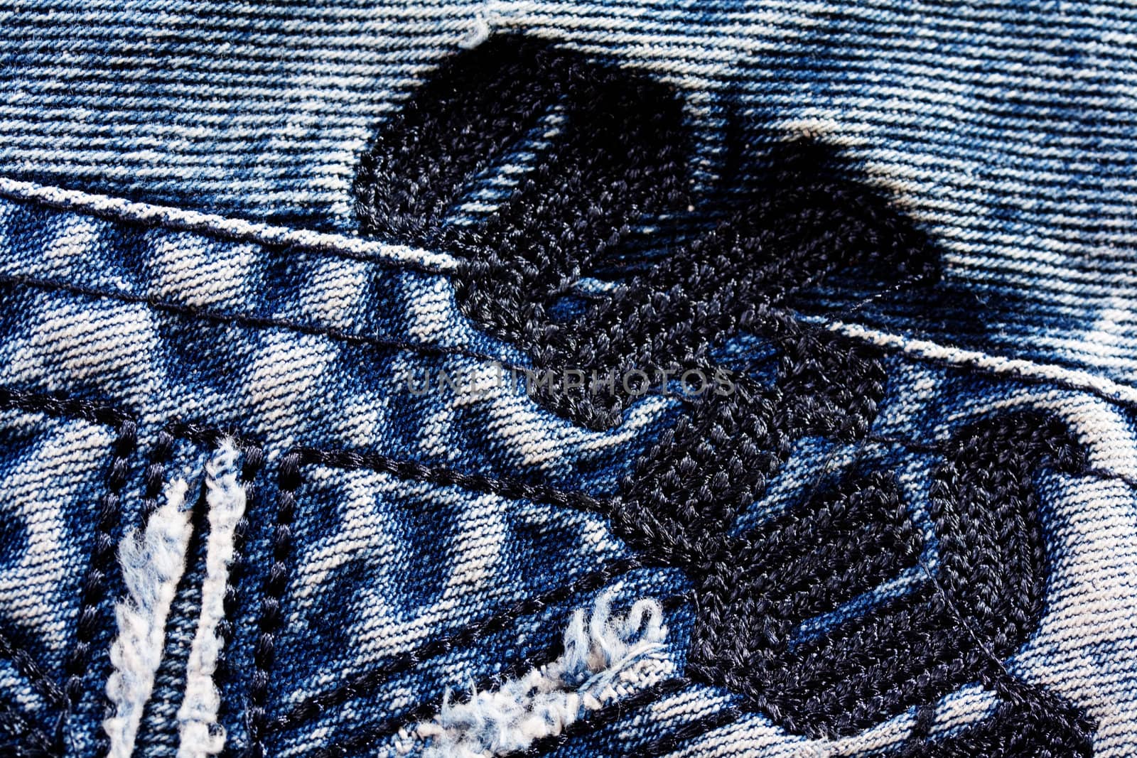 Creative embroidery on jeans, denim background