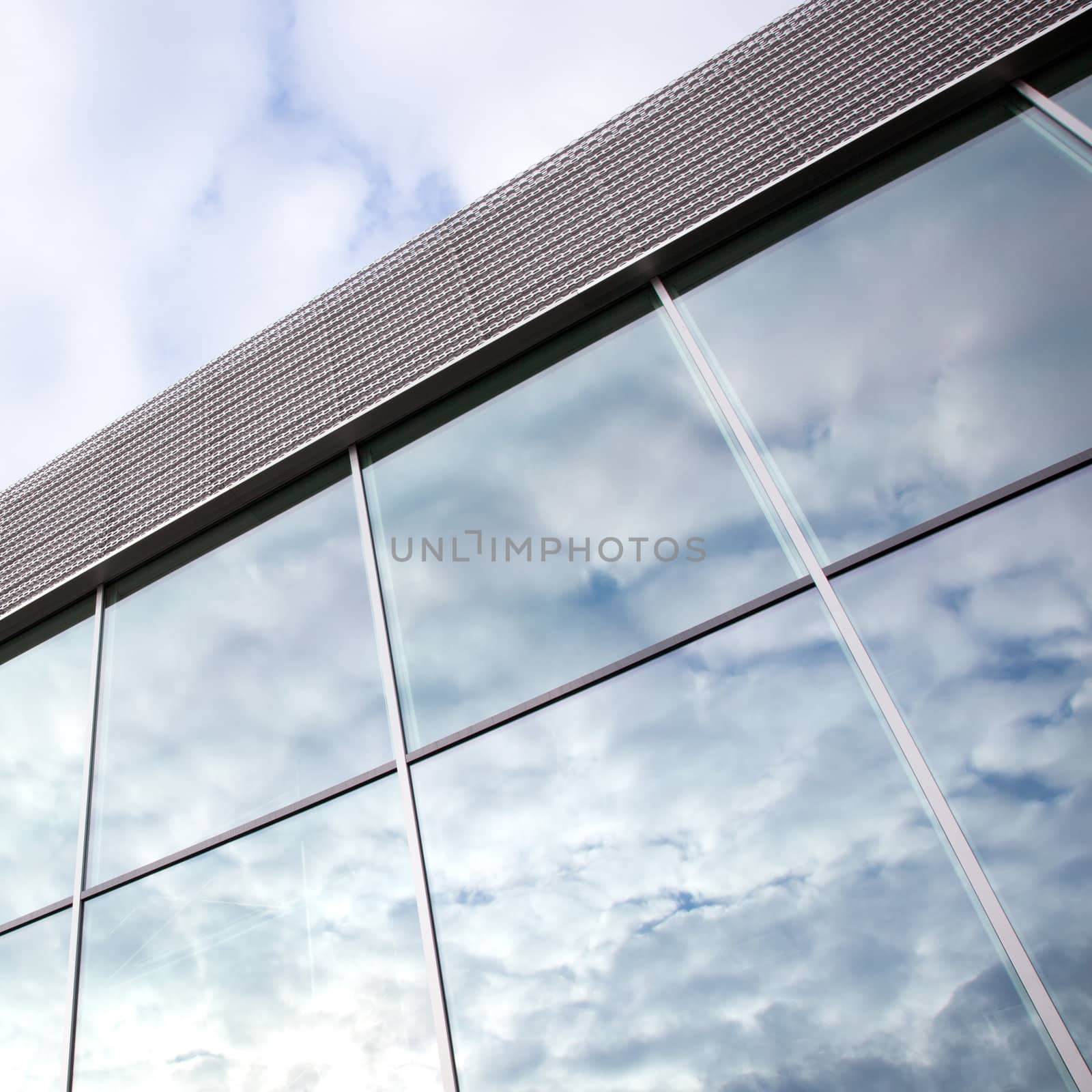 square picture of clouds reflected in windows of office building