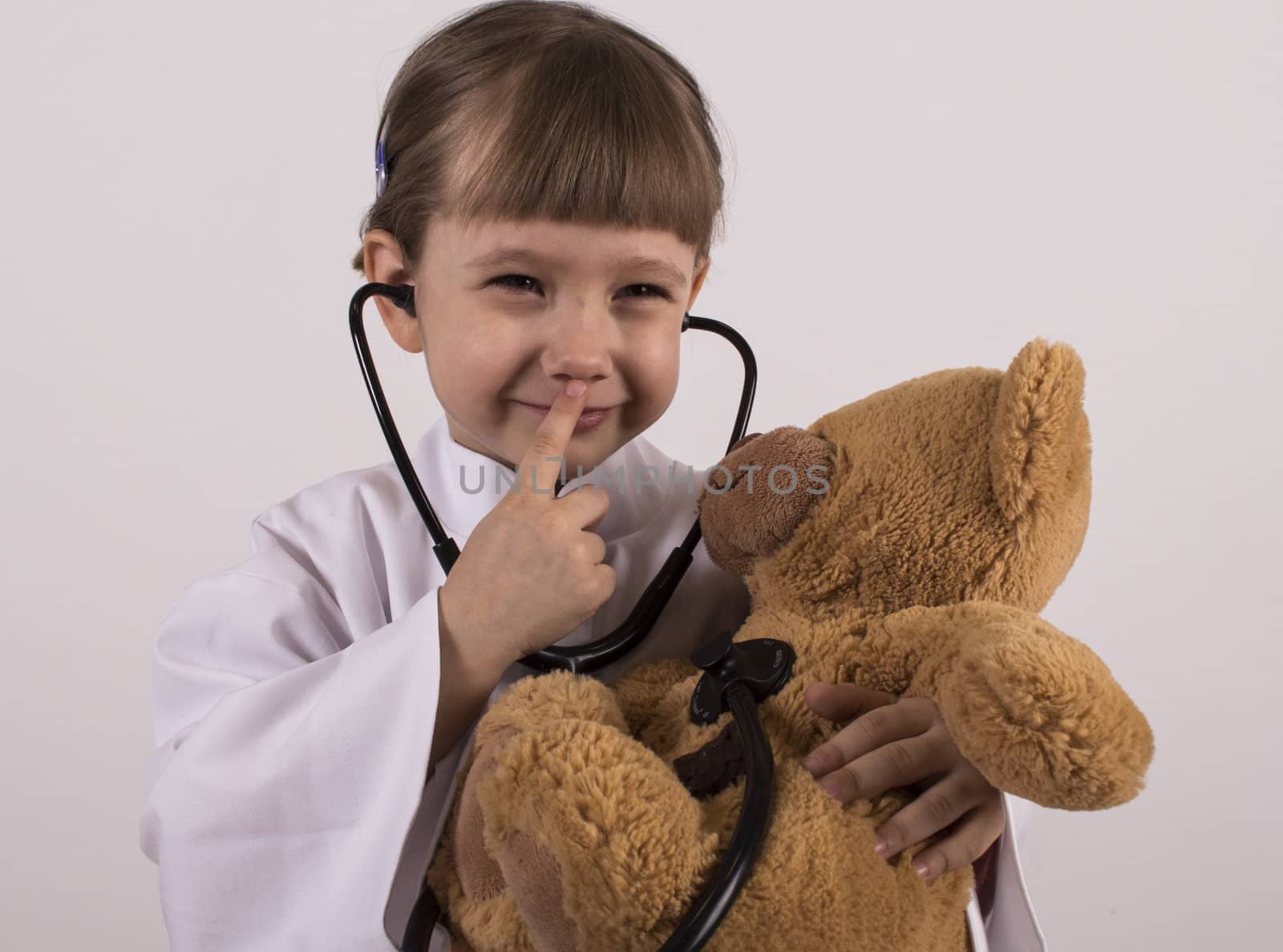 girl in overall is giveing phisical examination to her teddy bear