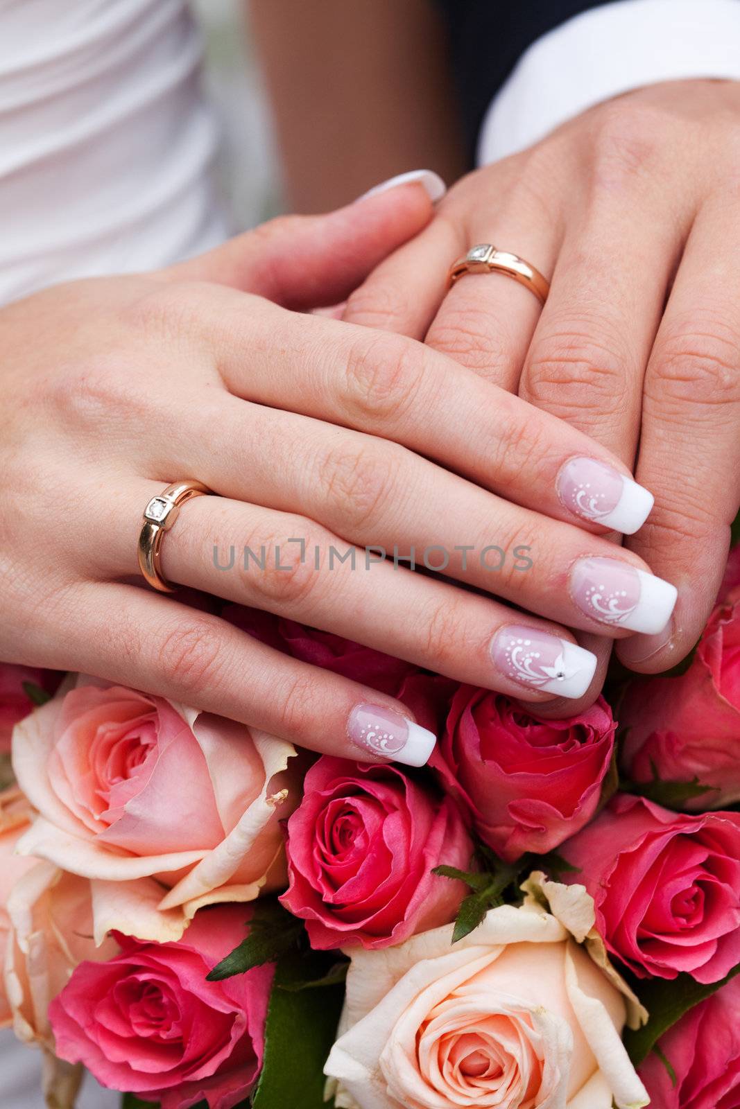 hands of the bride and groom with the rings lying on the bouquet by jannyjus