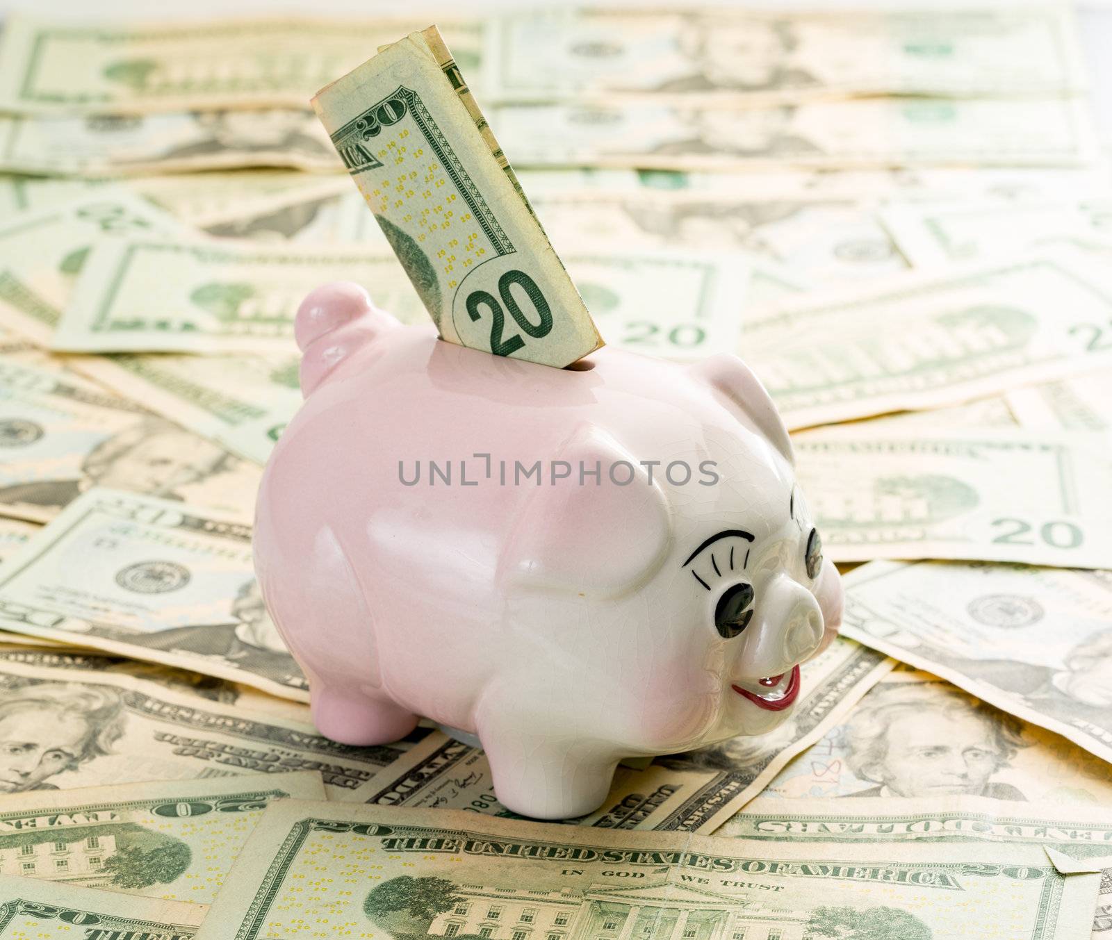 A single $20 bill inserted into the slot on a piggy bank with $20 dollar notes on table