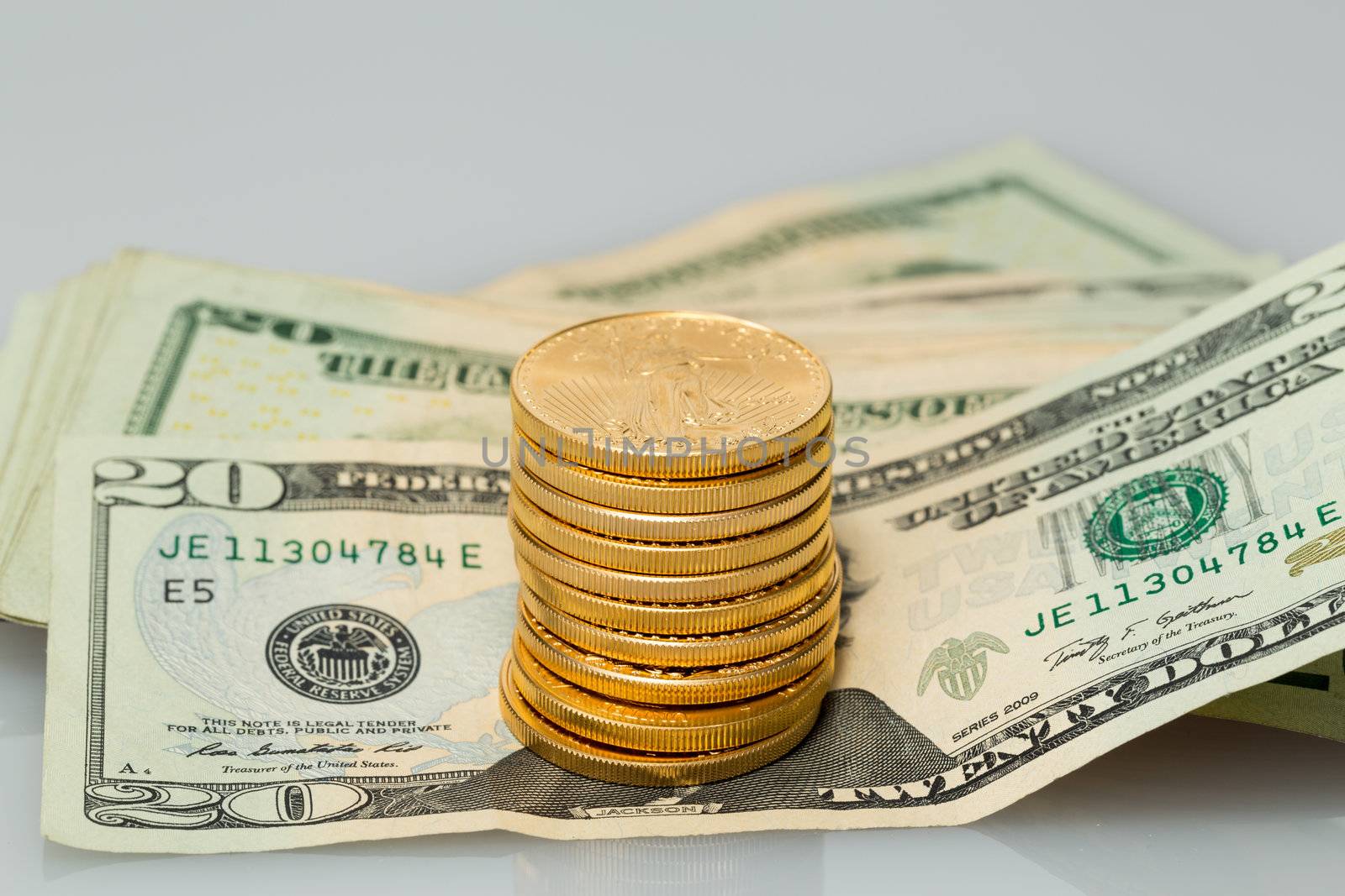 Gold coins standing on many $20 dollar bills and notes on white table