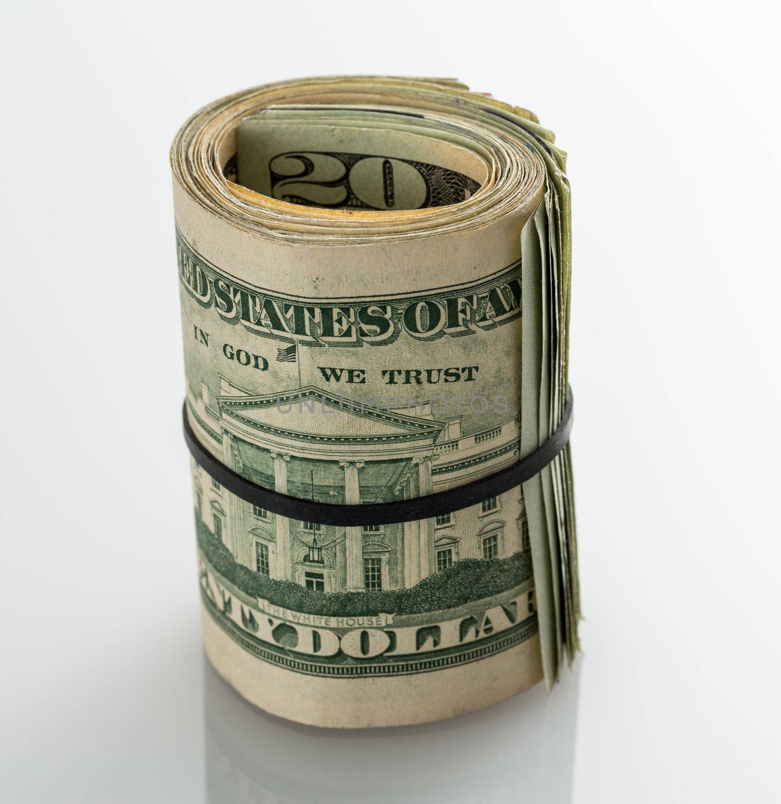 Roll of many $20 dollar bills and notes secured by elastic band on white table