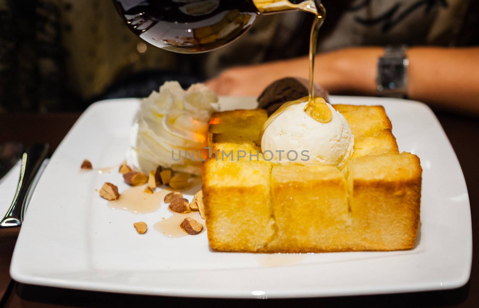 syrup being poured over a scoop of vanilla ice cream on toast