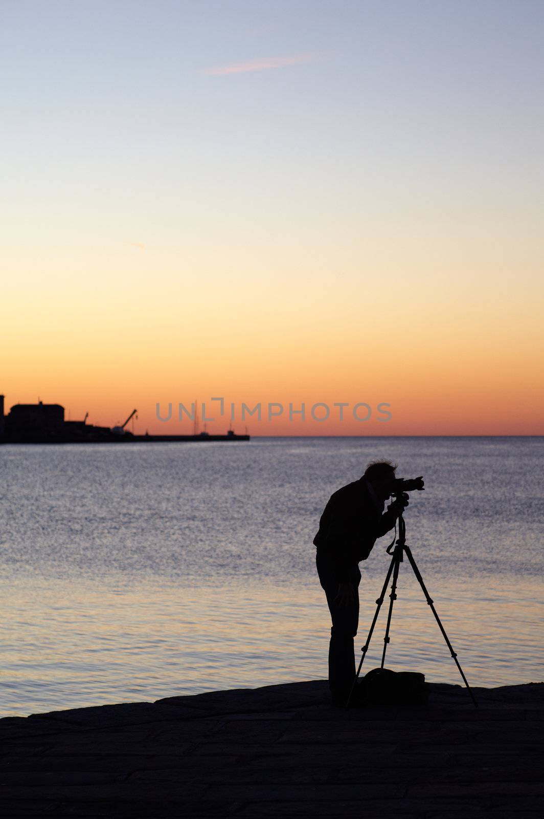 Photographer with camera and tripod take a picture at sunset