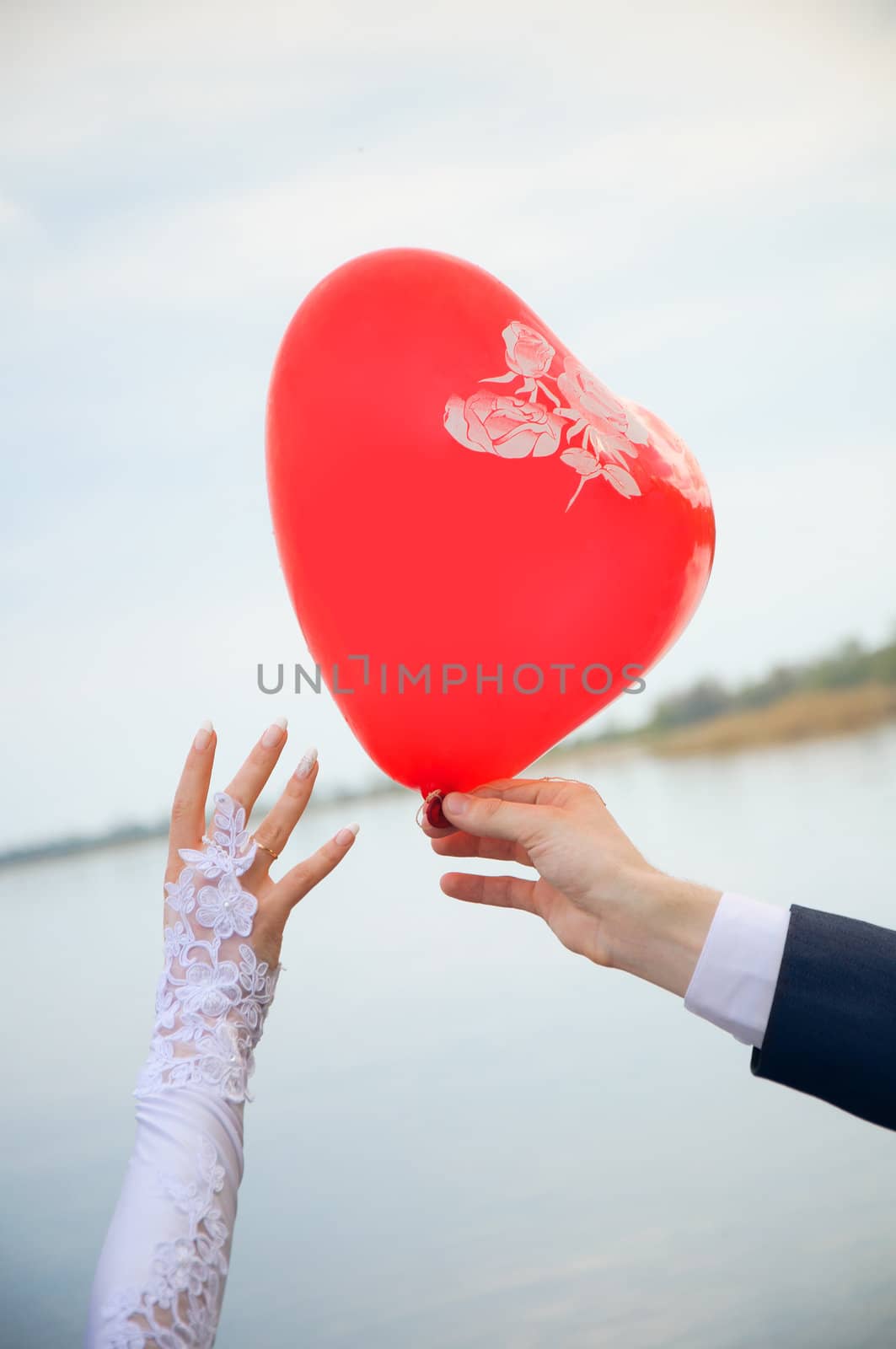 groom gives a balloon form of heart to bride. Wedding hands. Playful scene