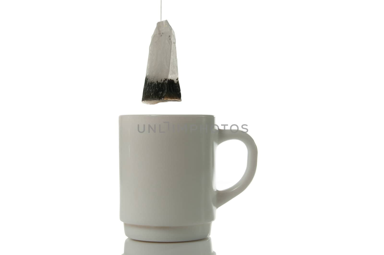 Tea bag over mug on a white background