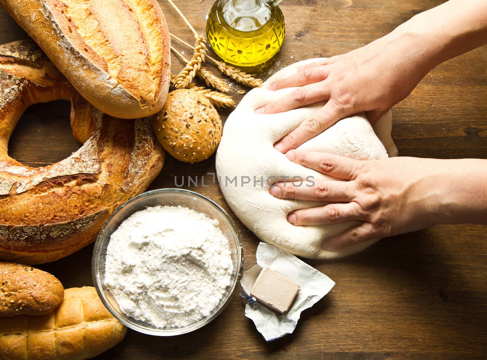 female hands in flour closeup kneading dough on table 
