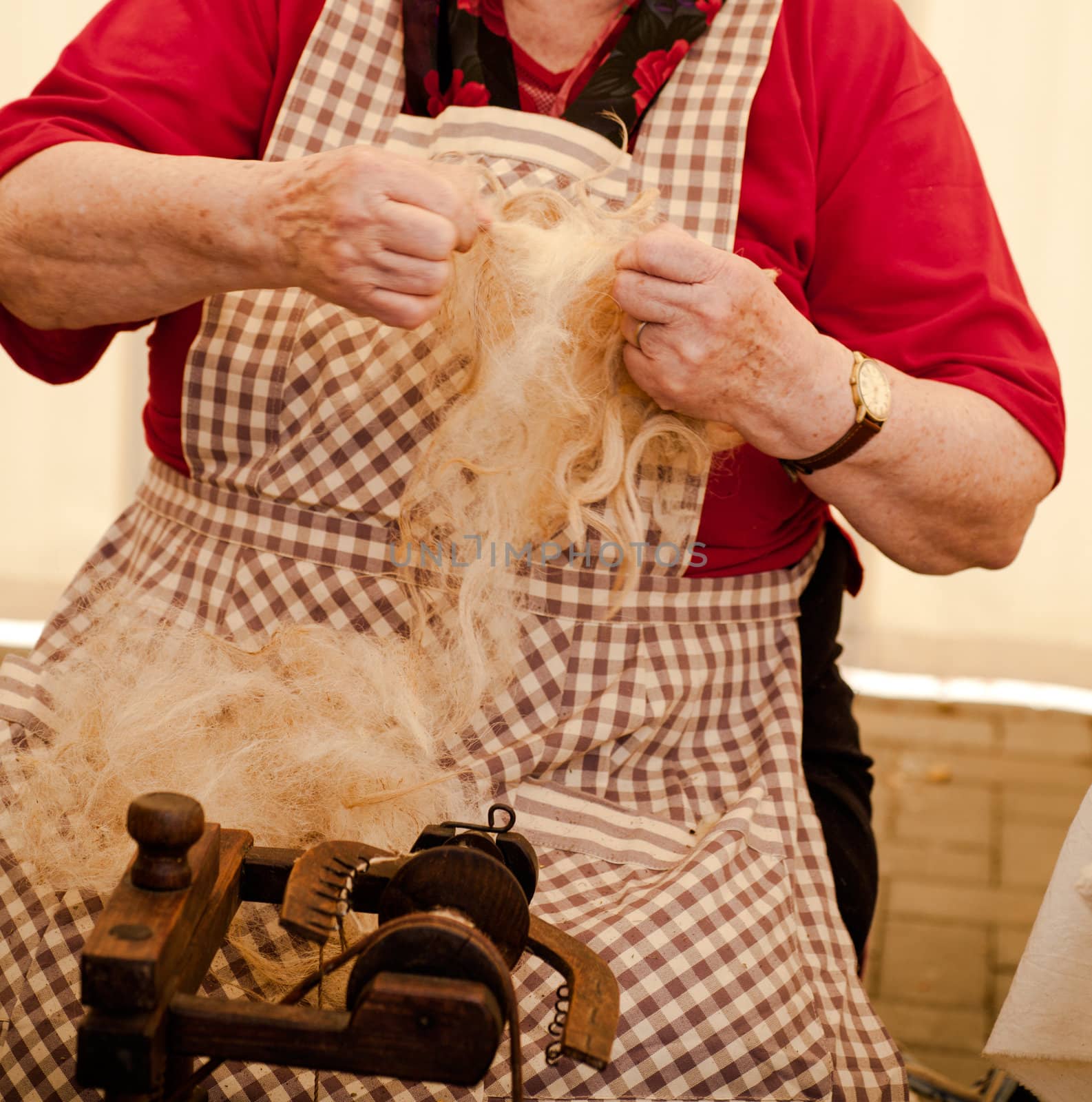 Elderly woman spinning wool by bepsimage