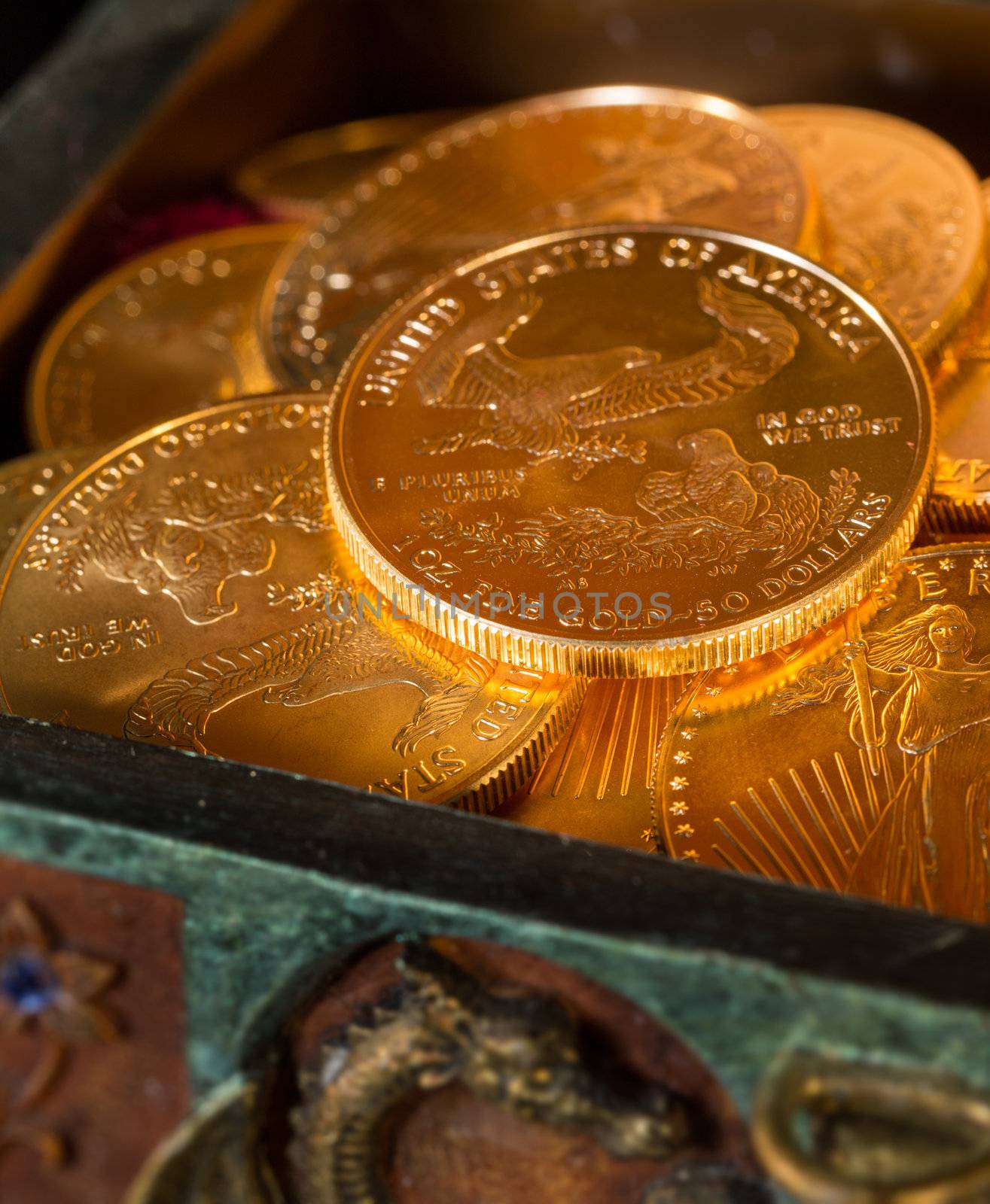Stacks of gold eagle one troy ounce golden coins from US Treasury mint in old carved pirate treasure chest